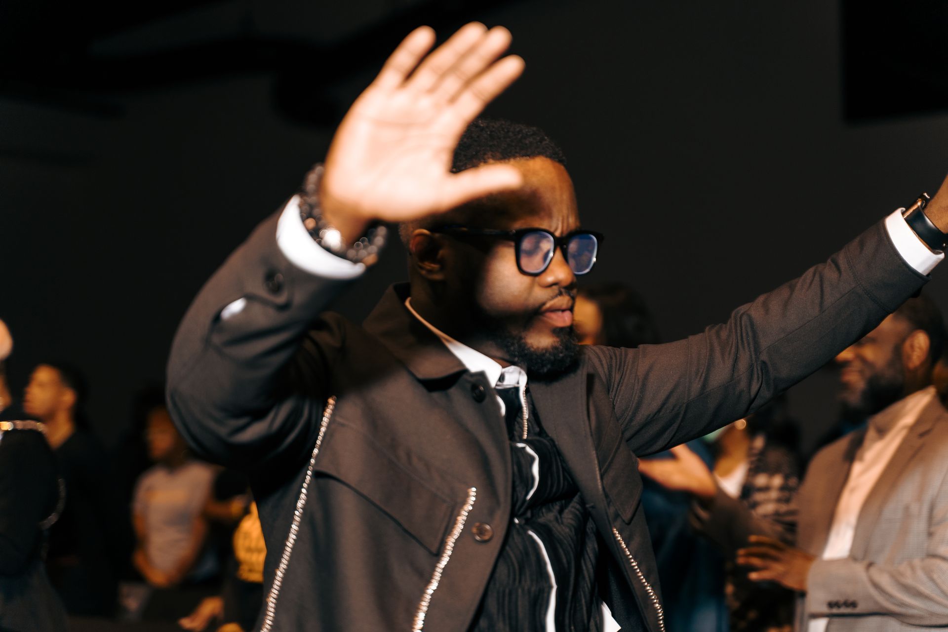 A man in a suit and tie is holding his hand up in the air.