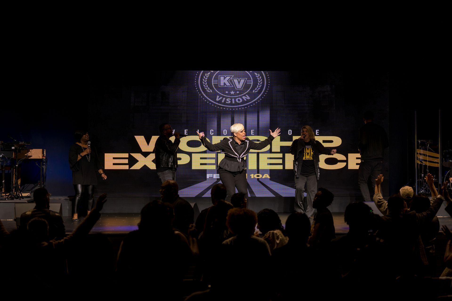 A man is standing on a stage in front of a crowd of people.