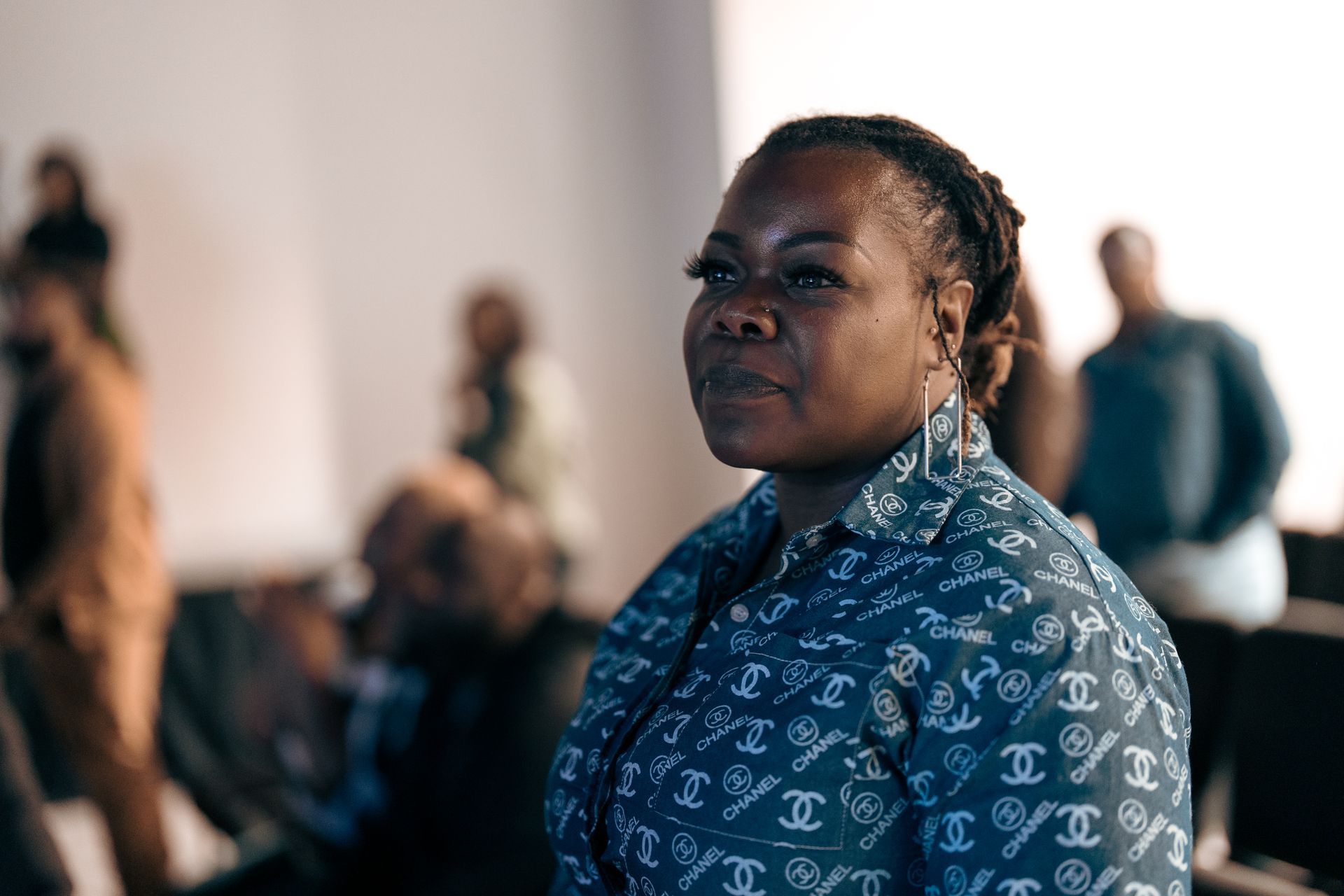 A woman in a blue shirt is sitting in front of a group of people.