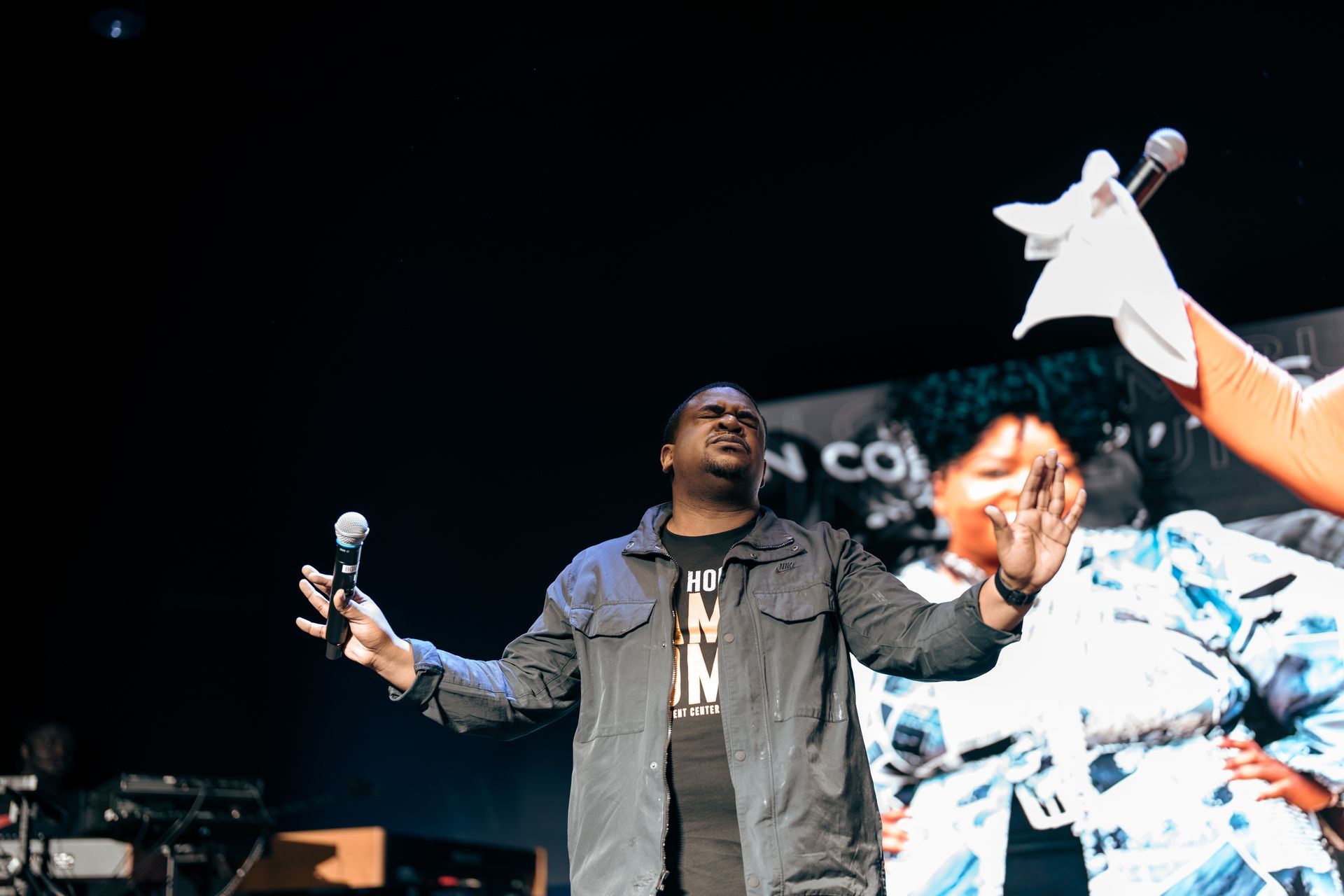 A man is standing on a stage holding two microphones.