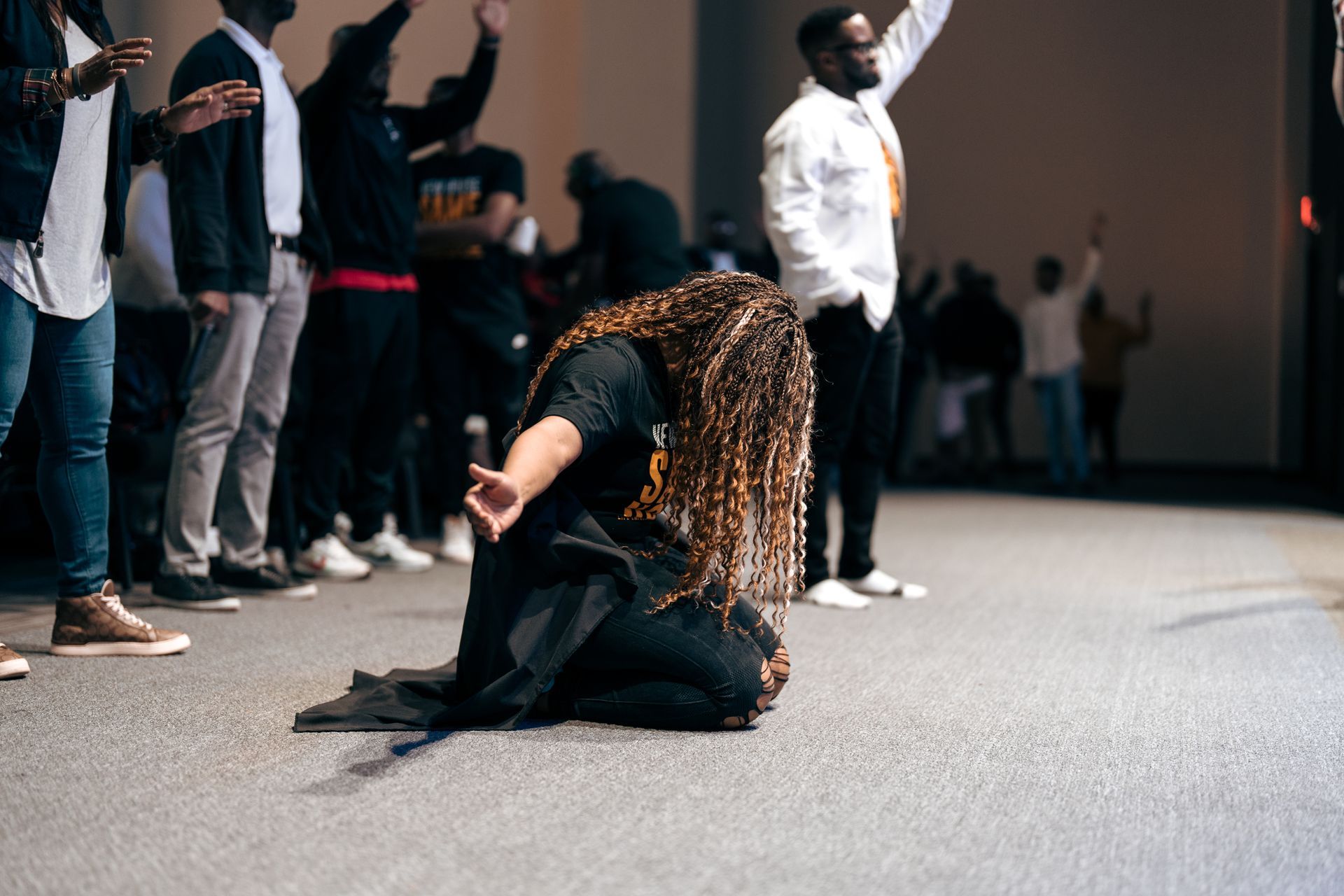 A woman is kneeling down in front of a crowd of people.