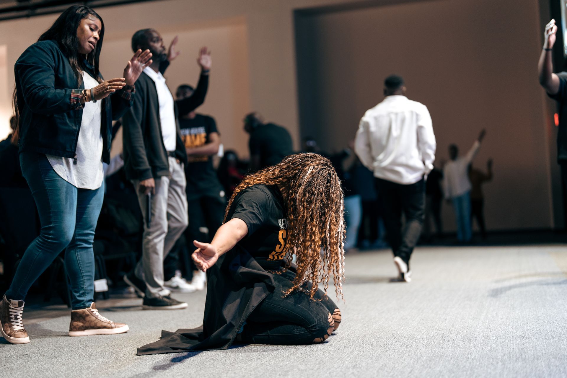 A woman is kneeling down in front of a crowd of people in a church.
