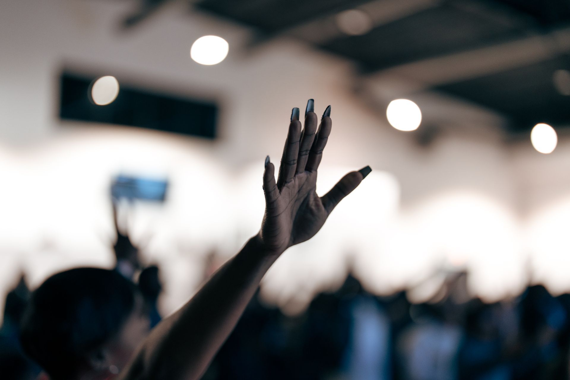 A woman is raising her hand in the air at a concert.