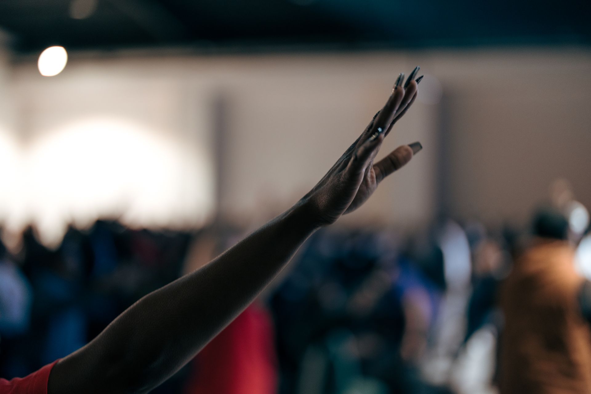 A person is raising their hand in the air in front of a crowd.