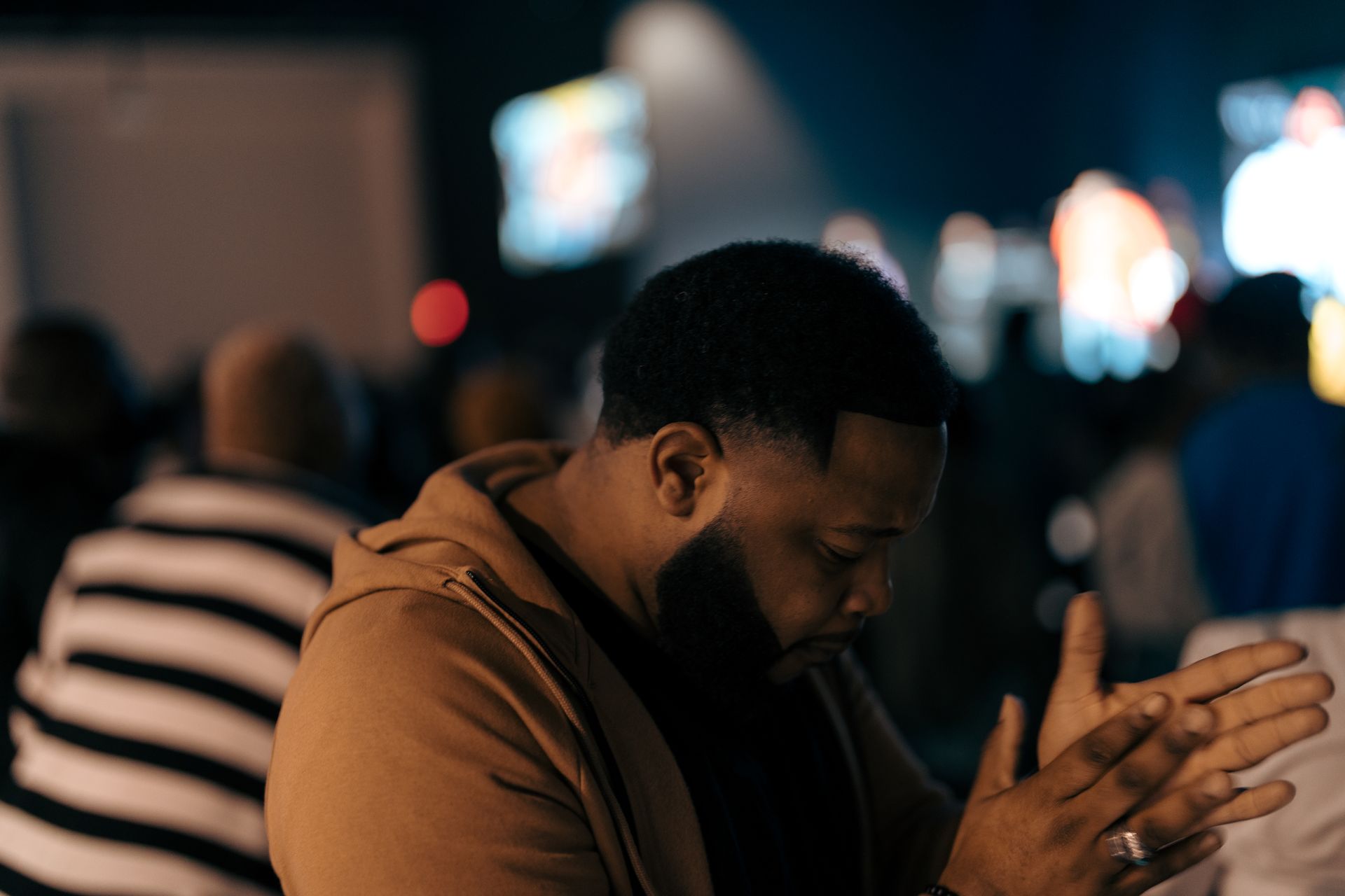 A man is praying in a church with his hands folded in prayer.