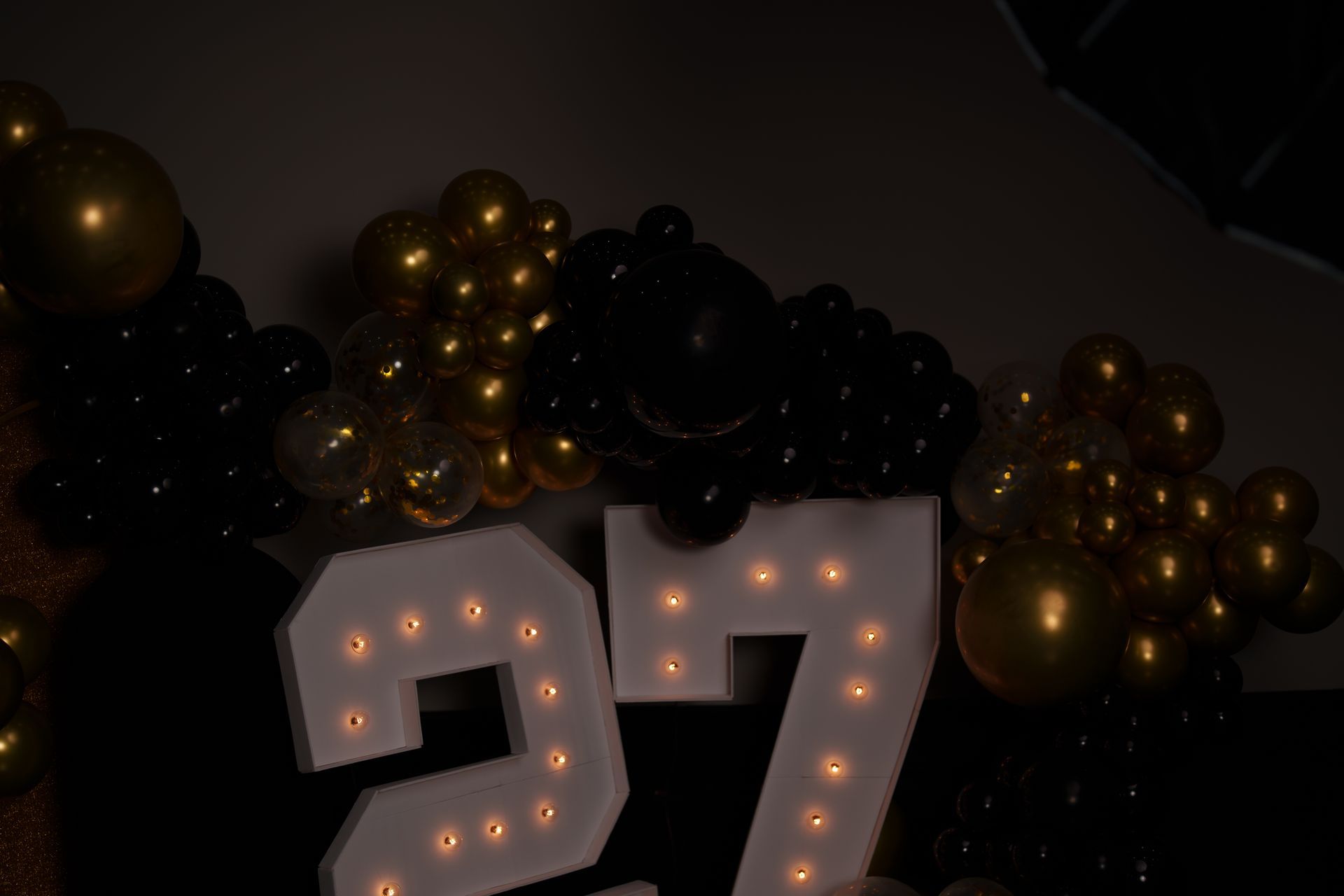 The number 27 is surrounded by black and gold balloons.