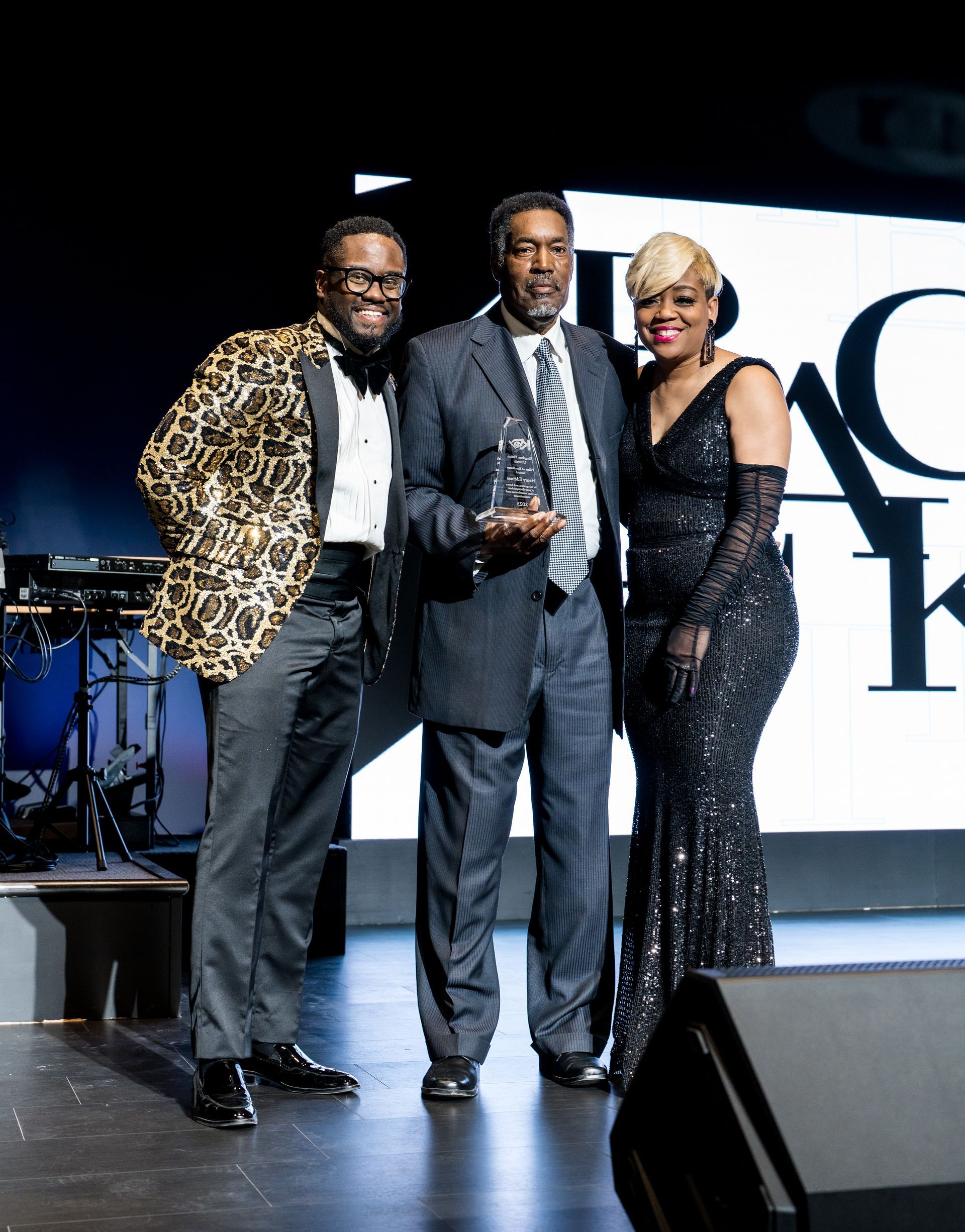 A group of people are standing on a stage holding a trophy.