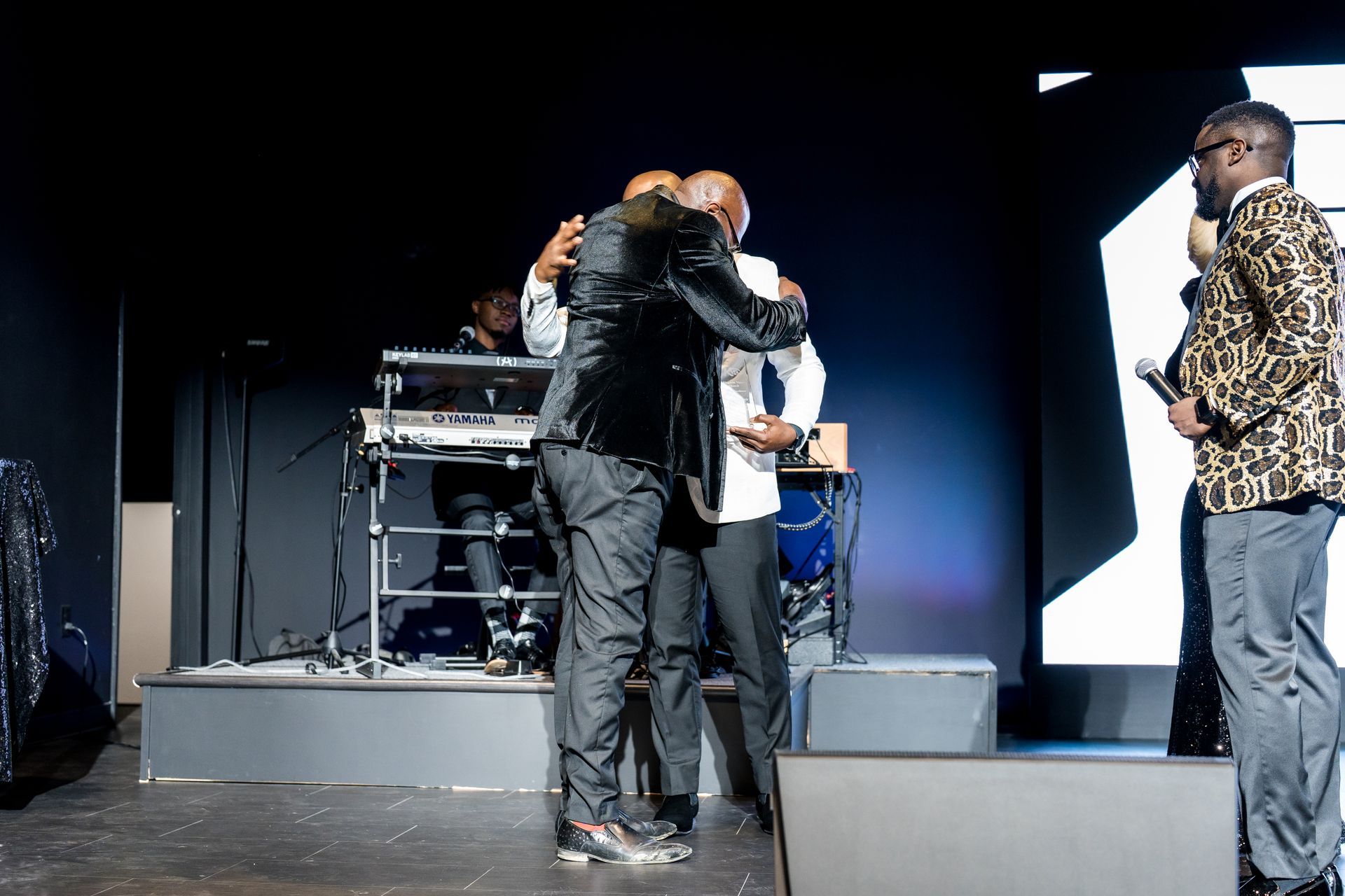 A group of men are hugging each other on a stage.