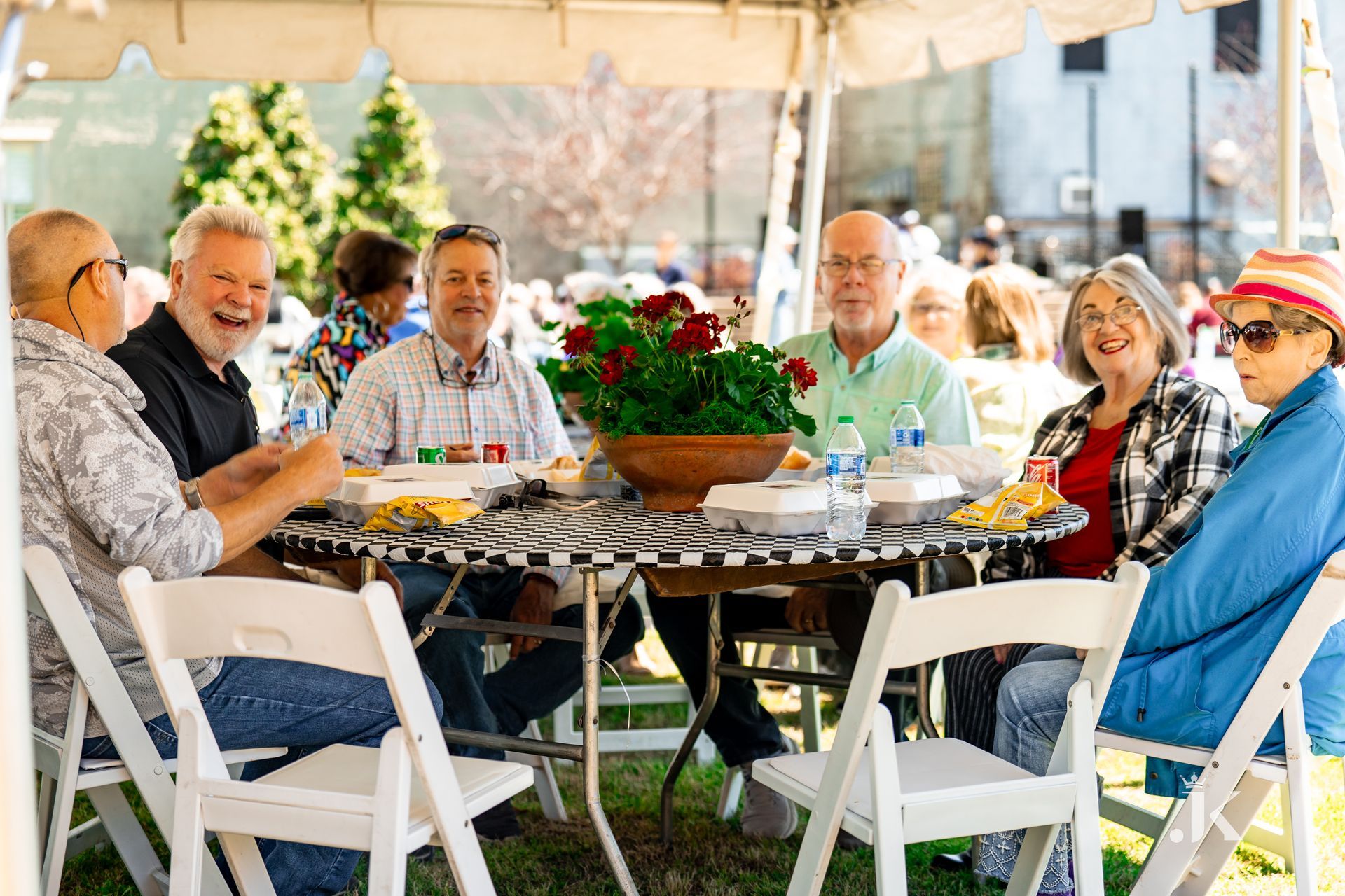 A group of people are sitting around a table under a tent.