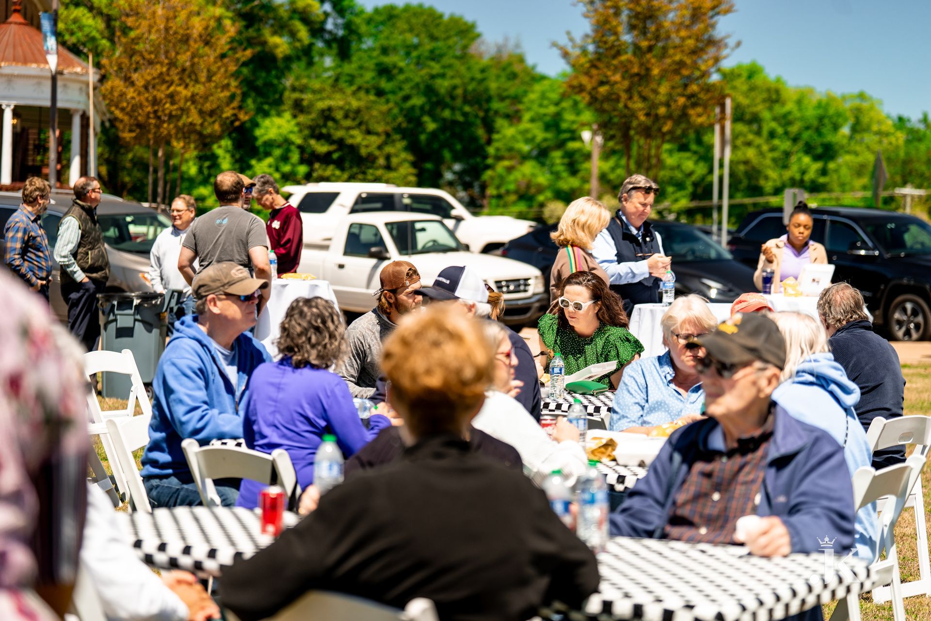 A group of people are sitting at tables in a park.
