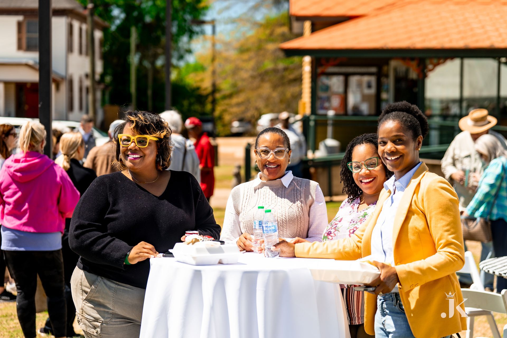 A group of women are standing around a table in a park.