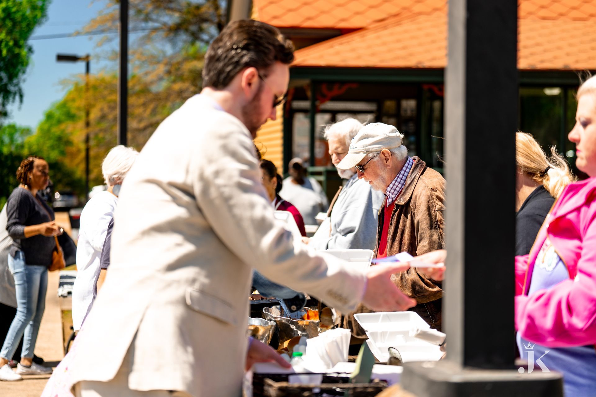 A man in a suit is serving food to a group of people.