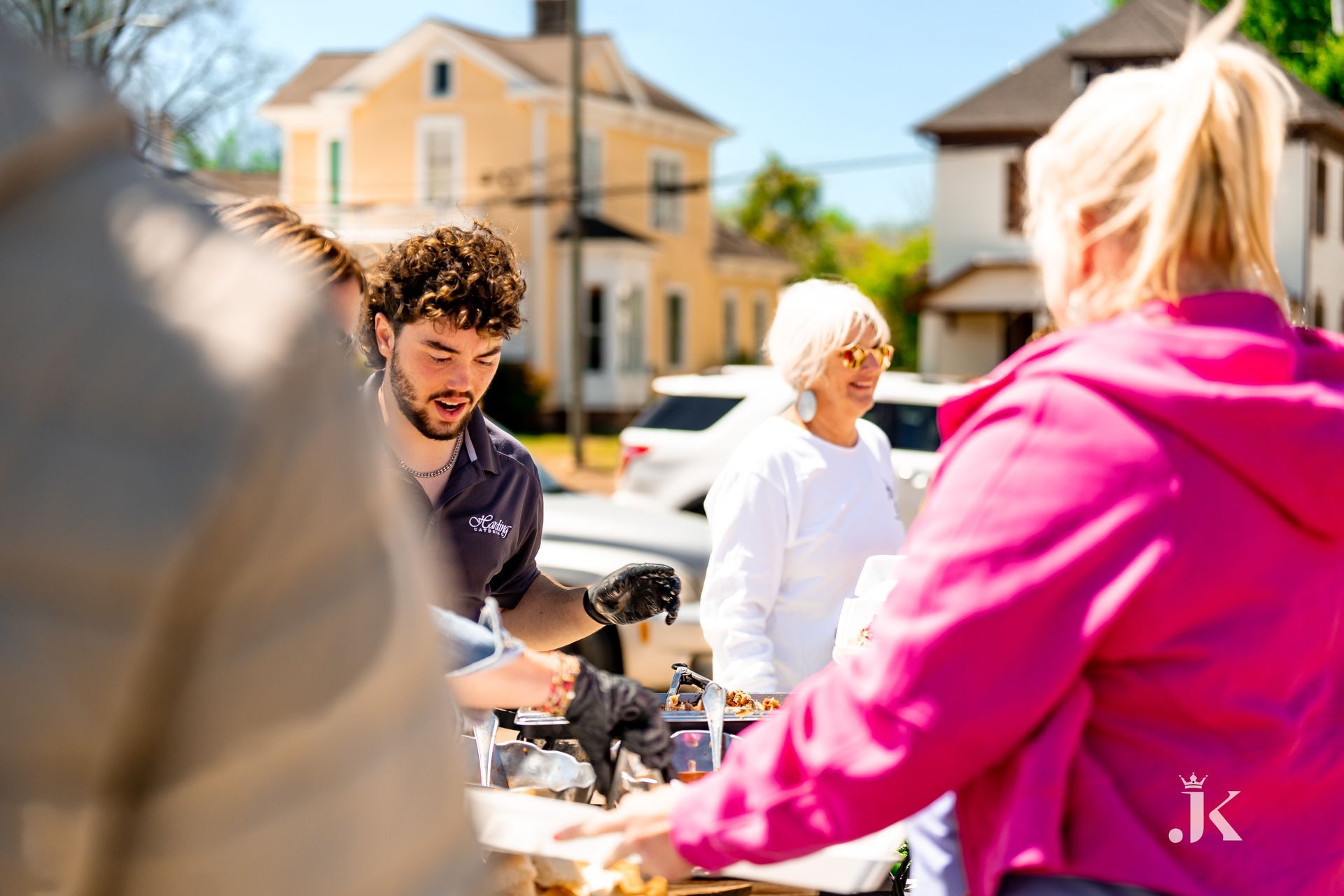 A group of people are standing around a table in a parking lot.