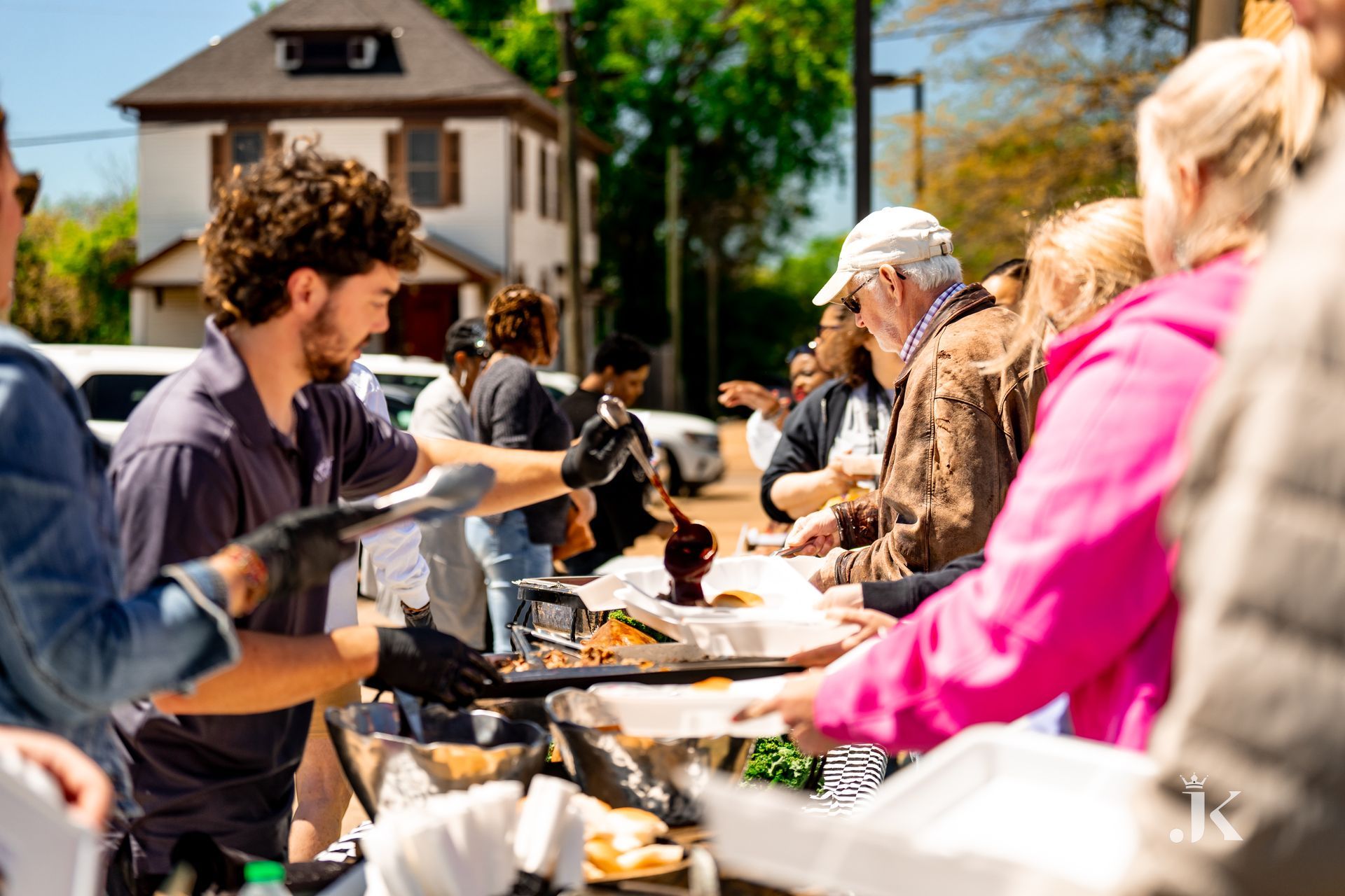 A group of people are standing around a table eating food.