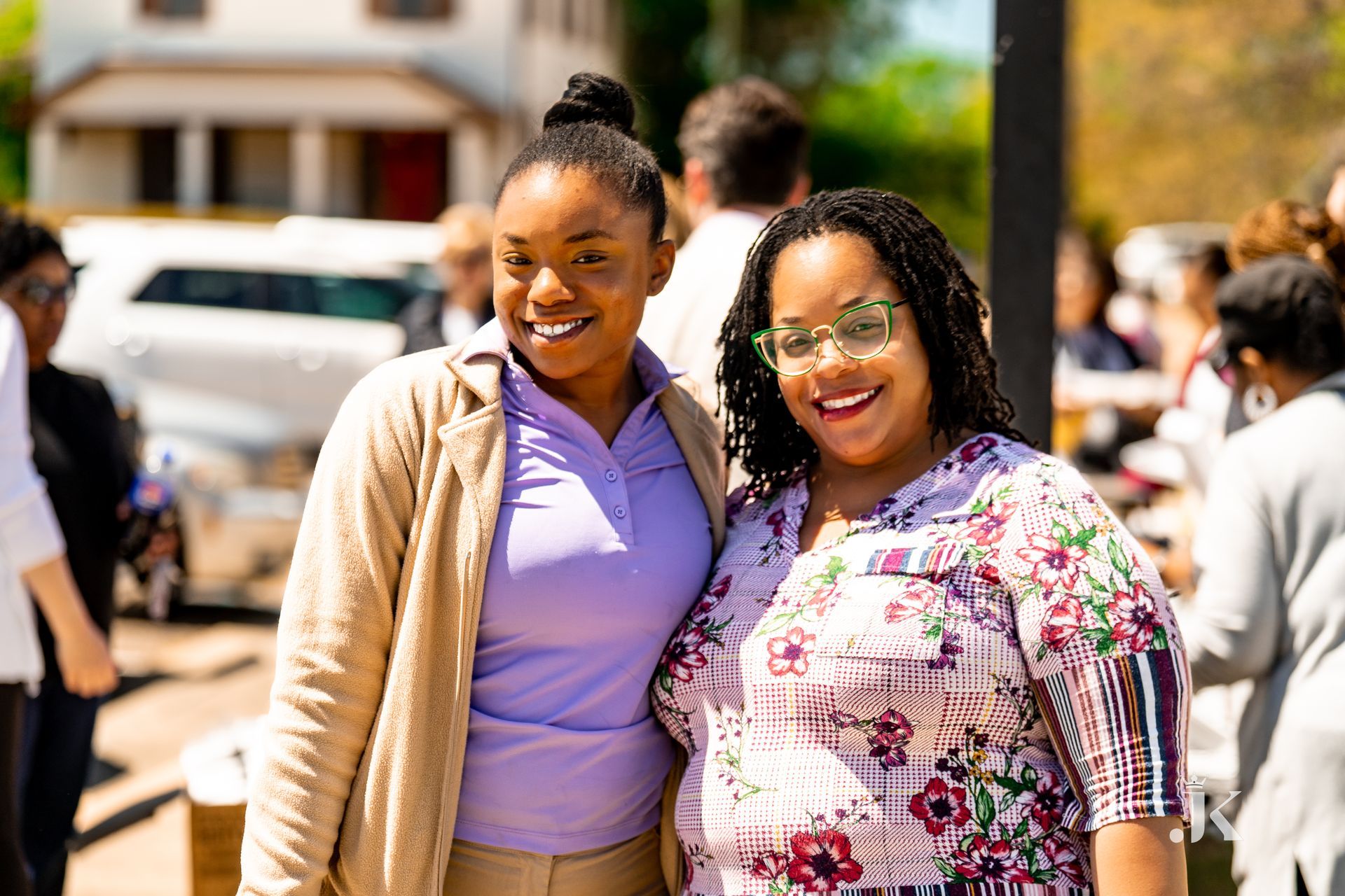 Two women are posing for a picture together in front of a crowd of people.