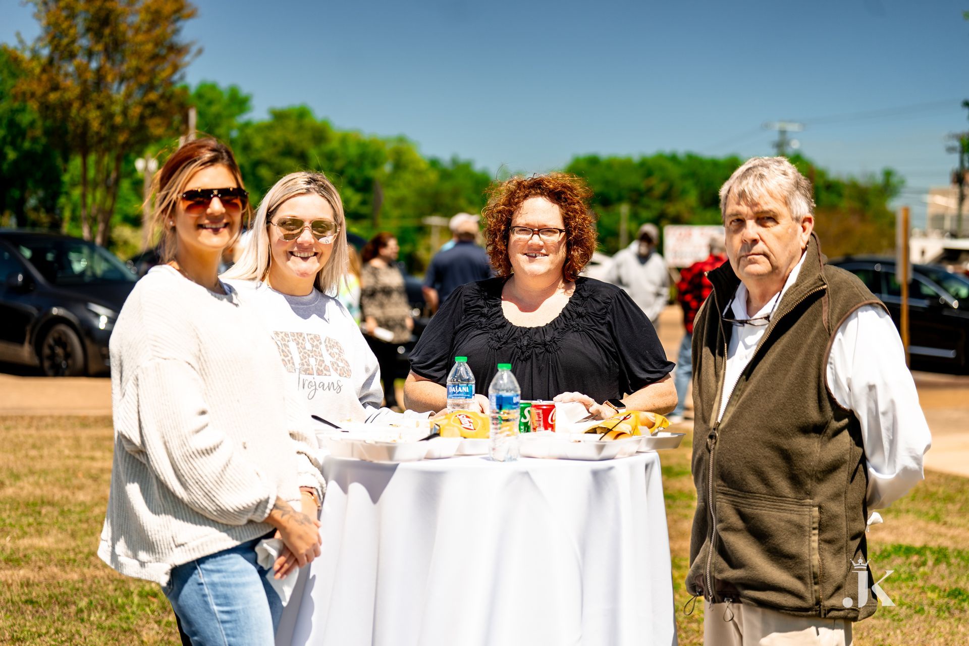 A group of people are standing around a table in a park.