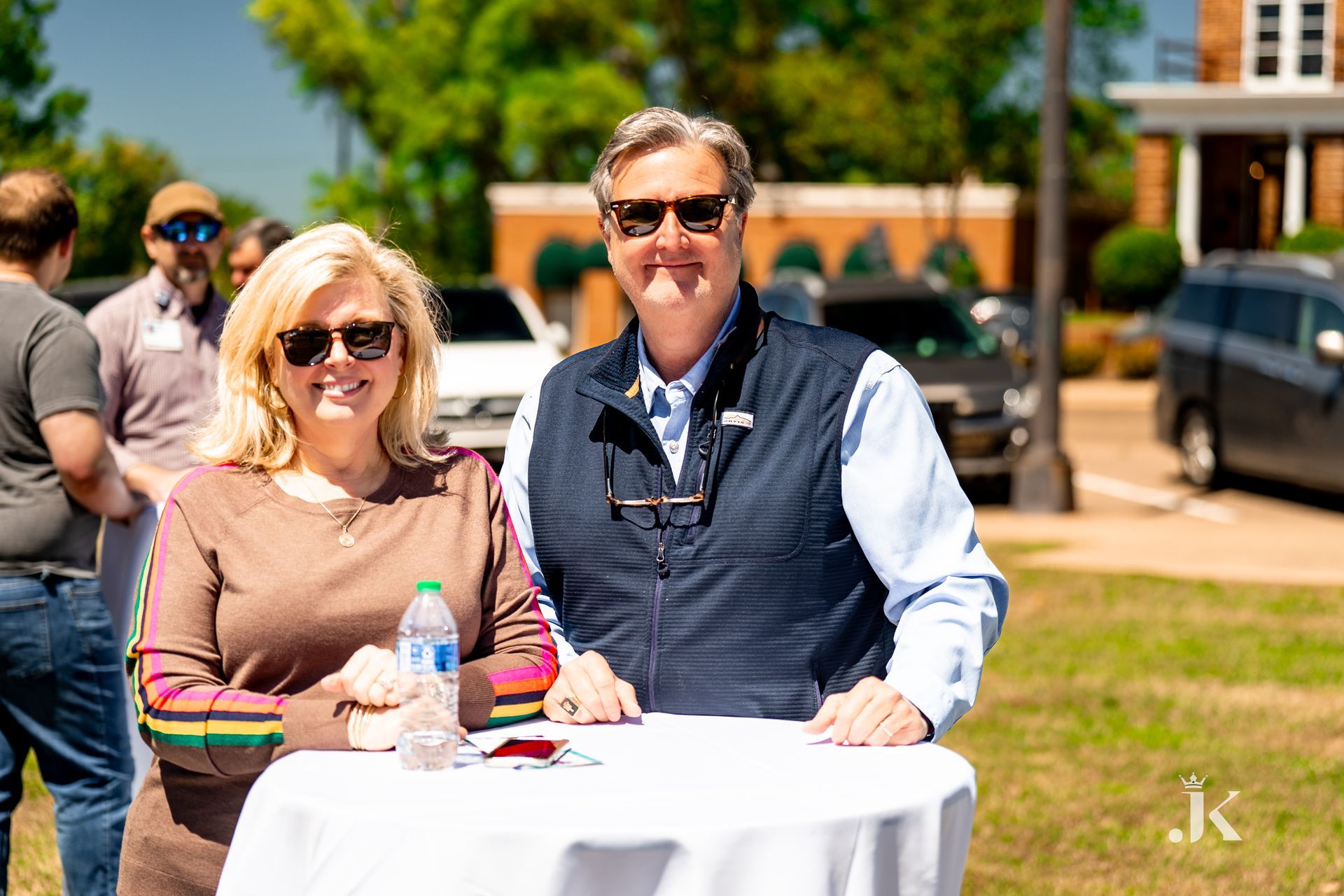 A man and a woman are sitting at a table in a park.