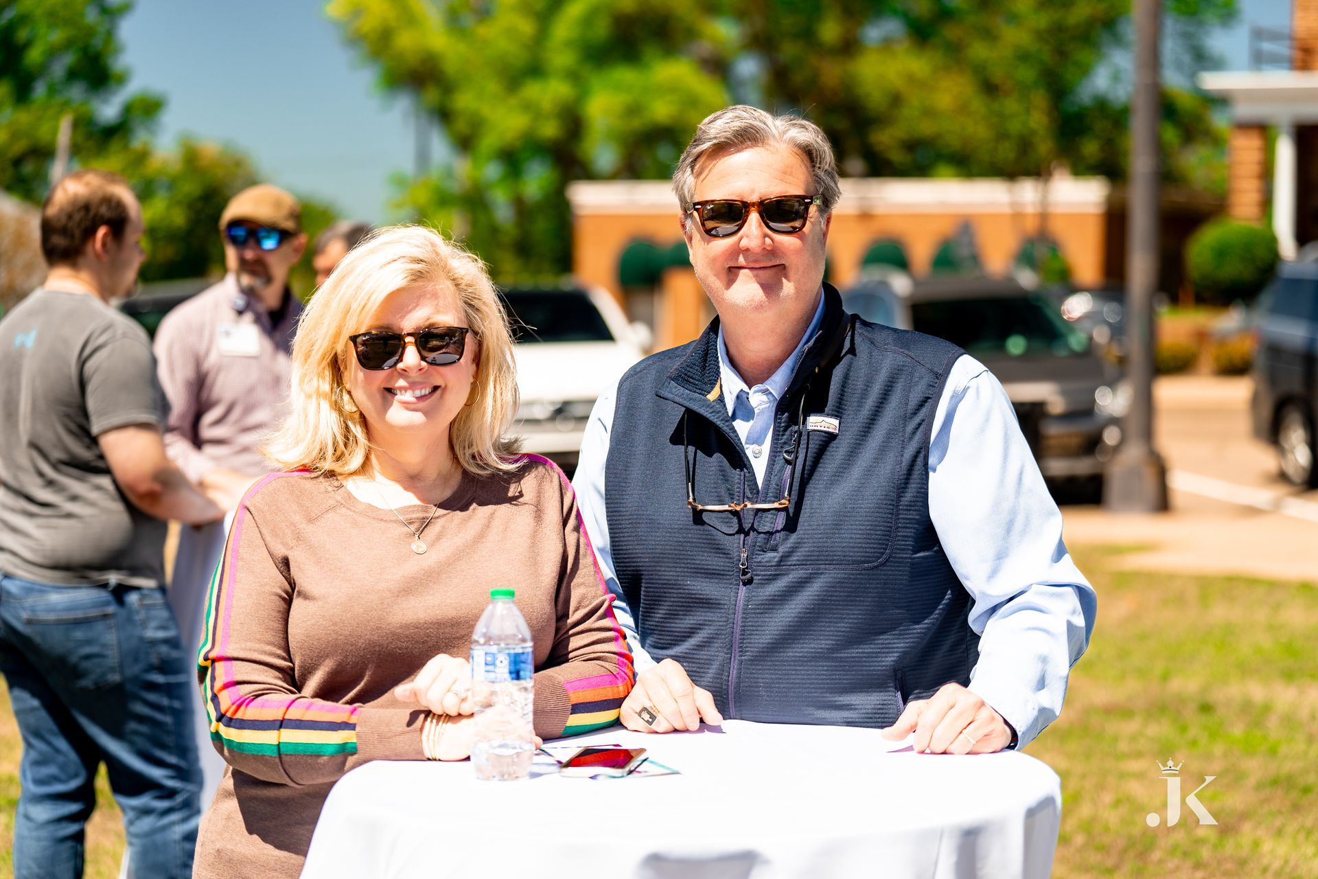 A man and a woman are sitting at a table in a park.