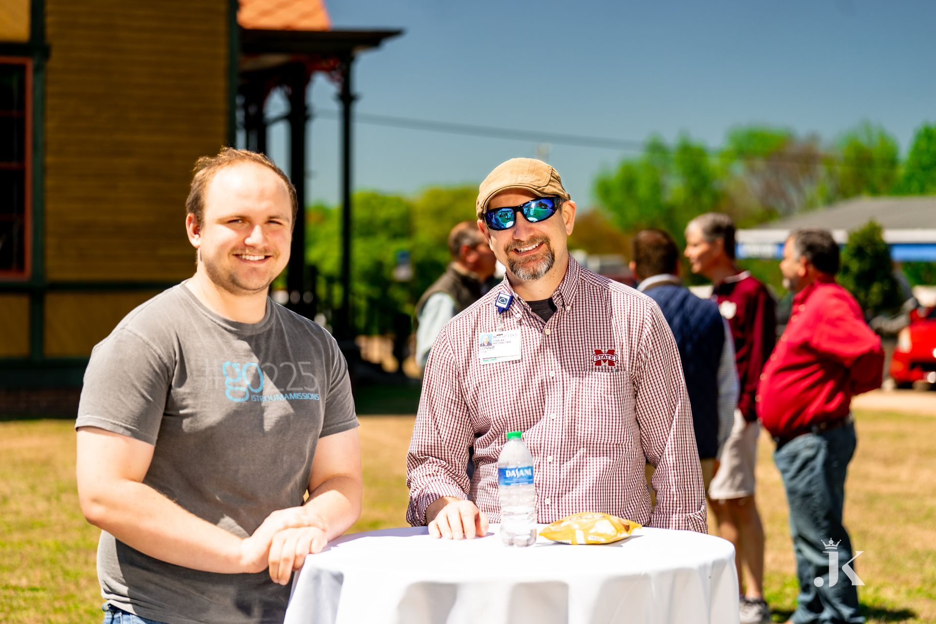 Two men are standing next to each other in front of a table.