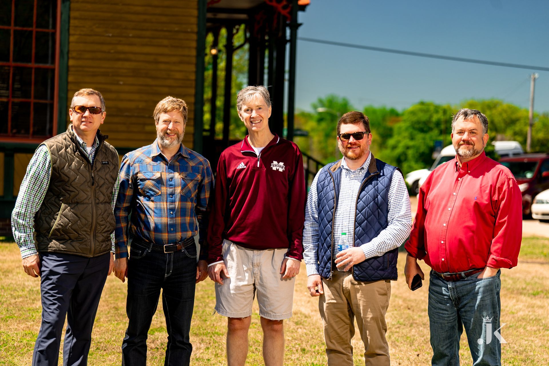 A group of men are posing for a picture in front of a building.