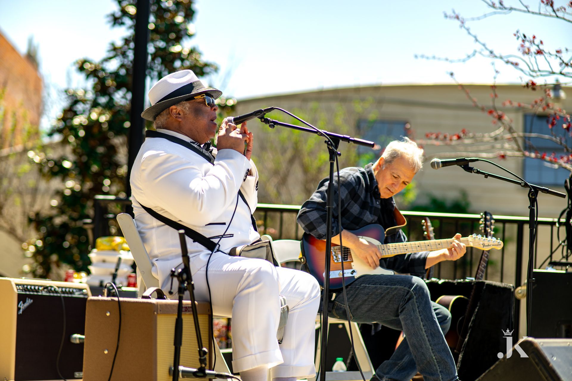 Two men are playing guitars and singing into microphones on a stage.