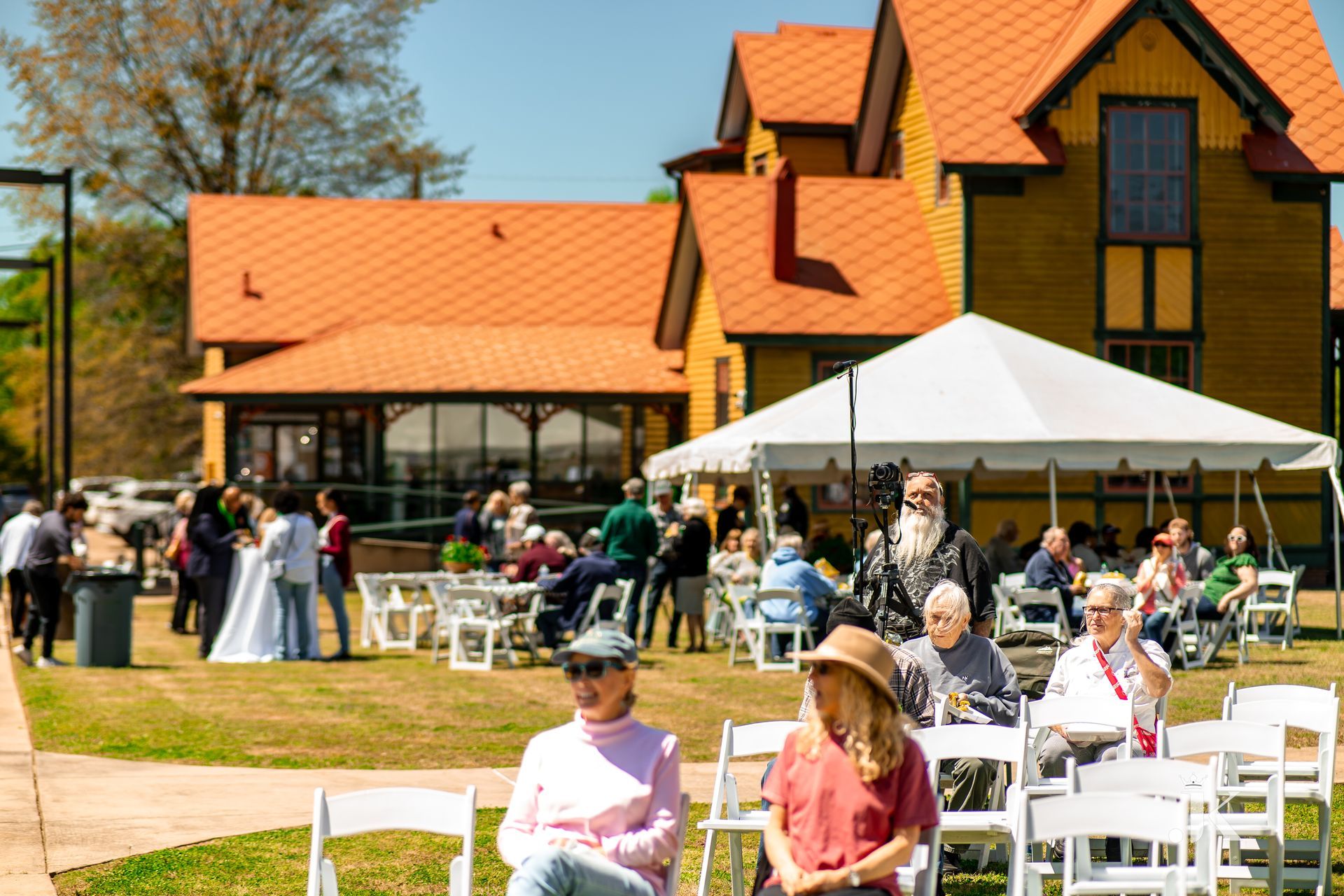 A group of people are sitting in chairs in front of a large house.