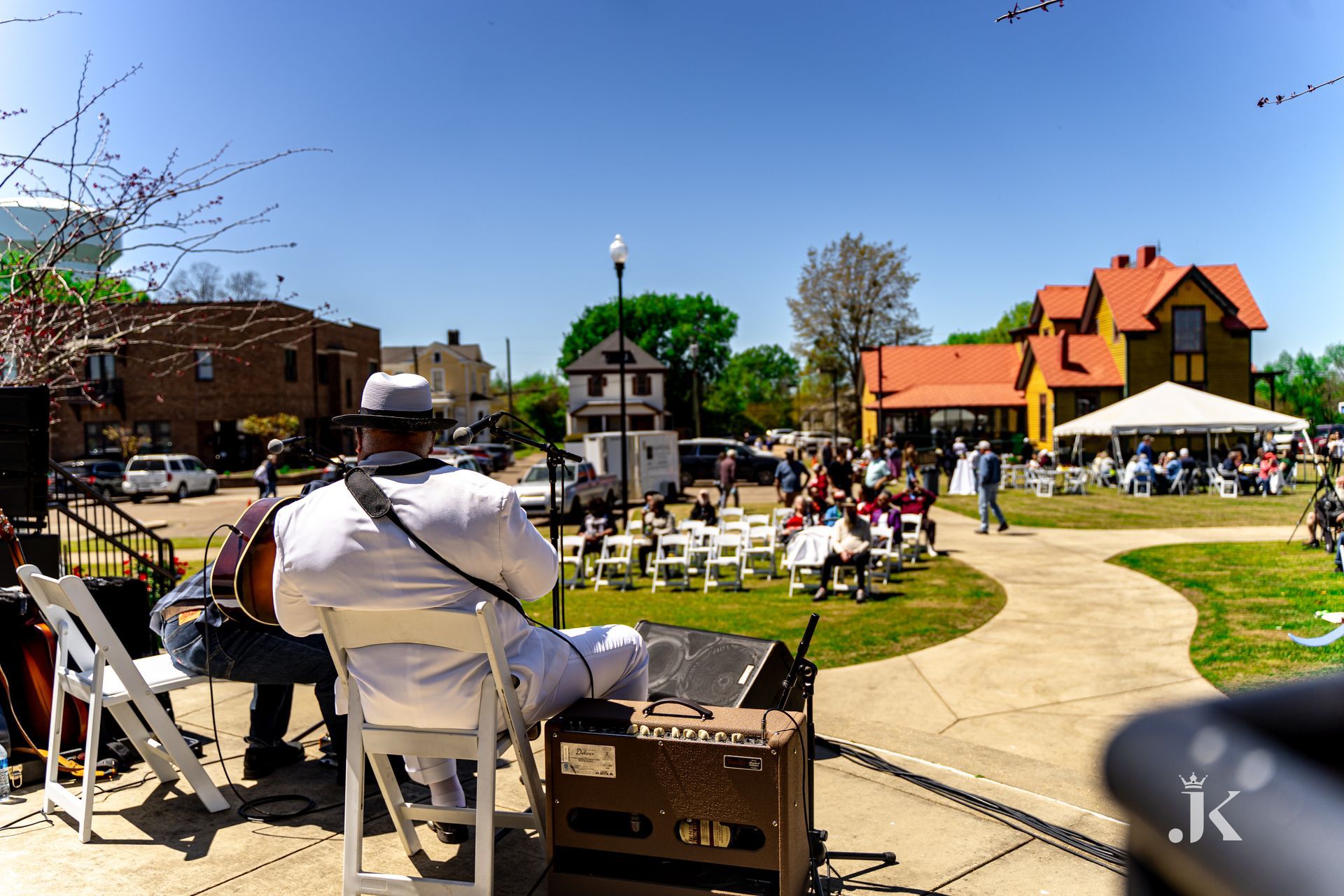 A man is sitting in a chair playing a guitar in a park.