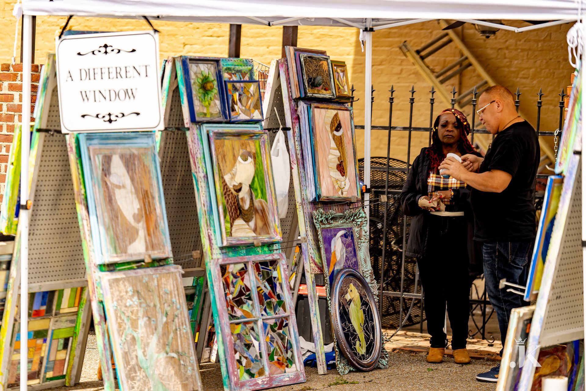 A man and a woman are standing under a tent with paintings on it.