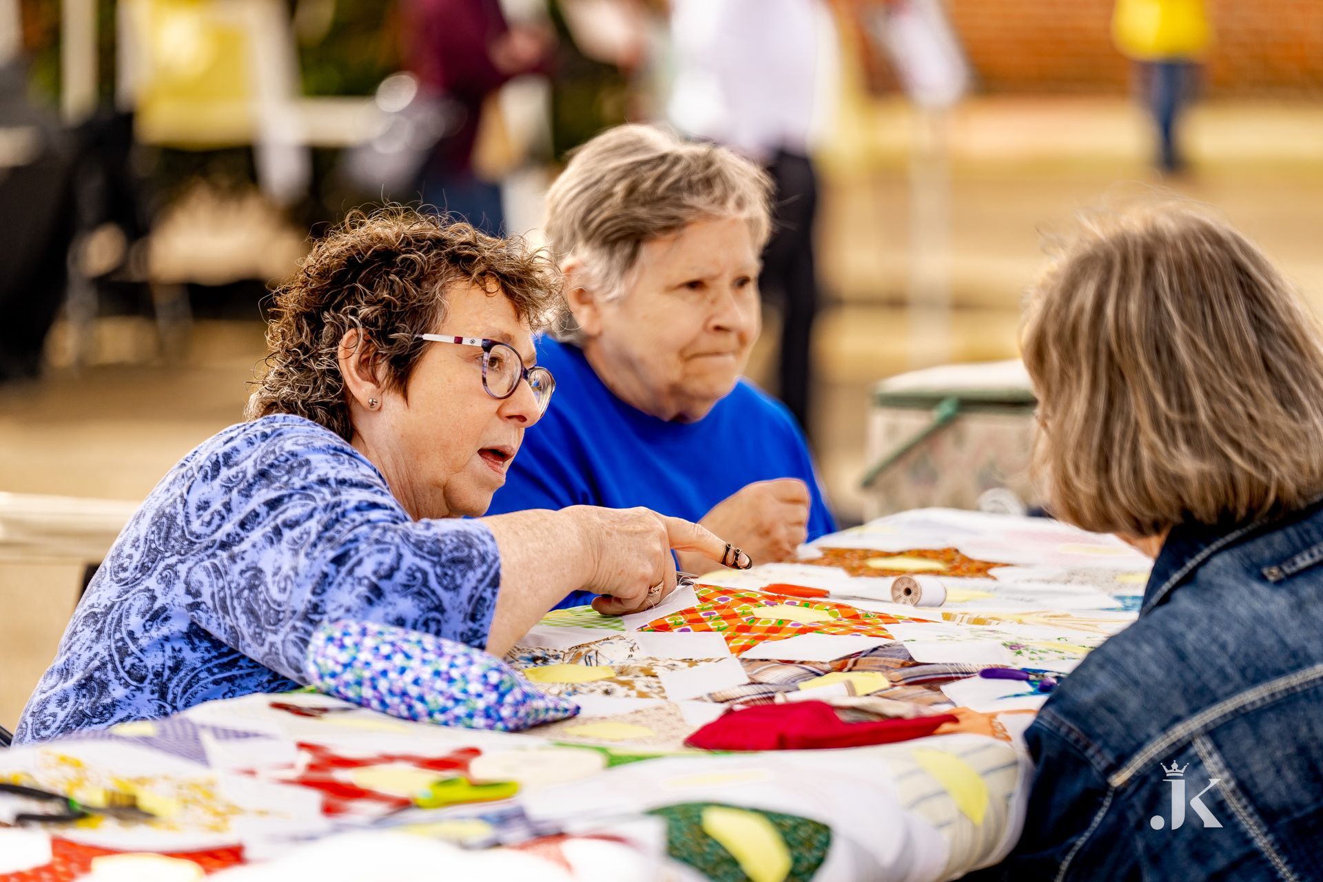 Three older women are sitting at a table talking to each other.