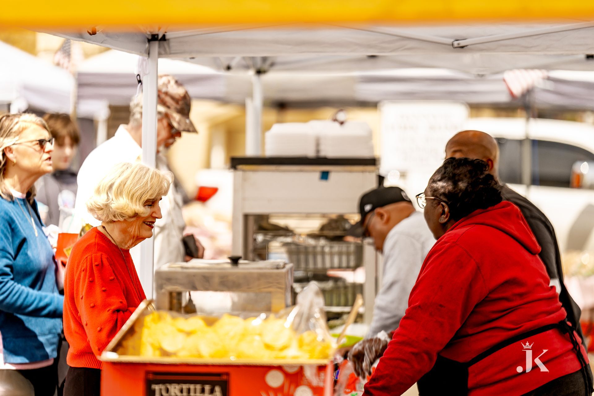 A group of people are standing around a tortilla stand at a market.