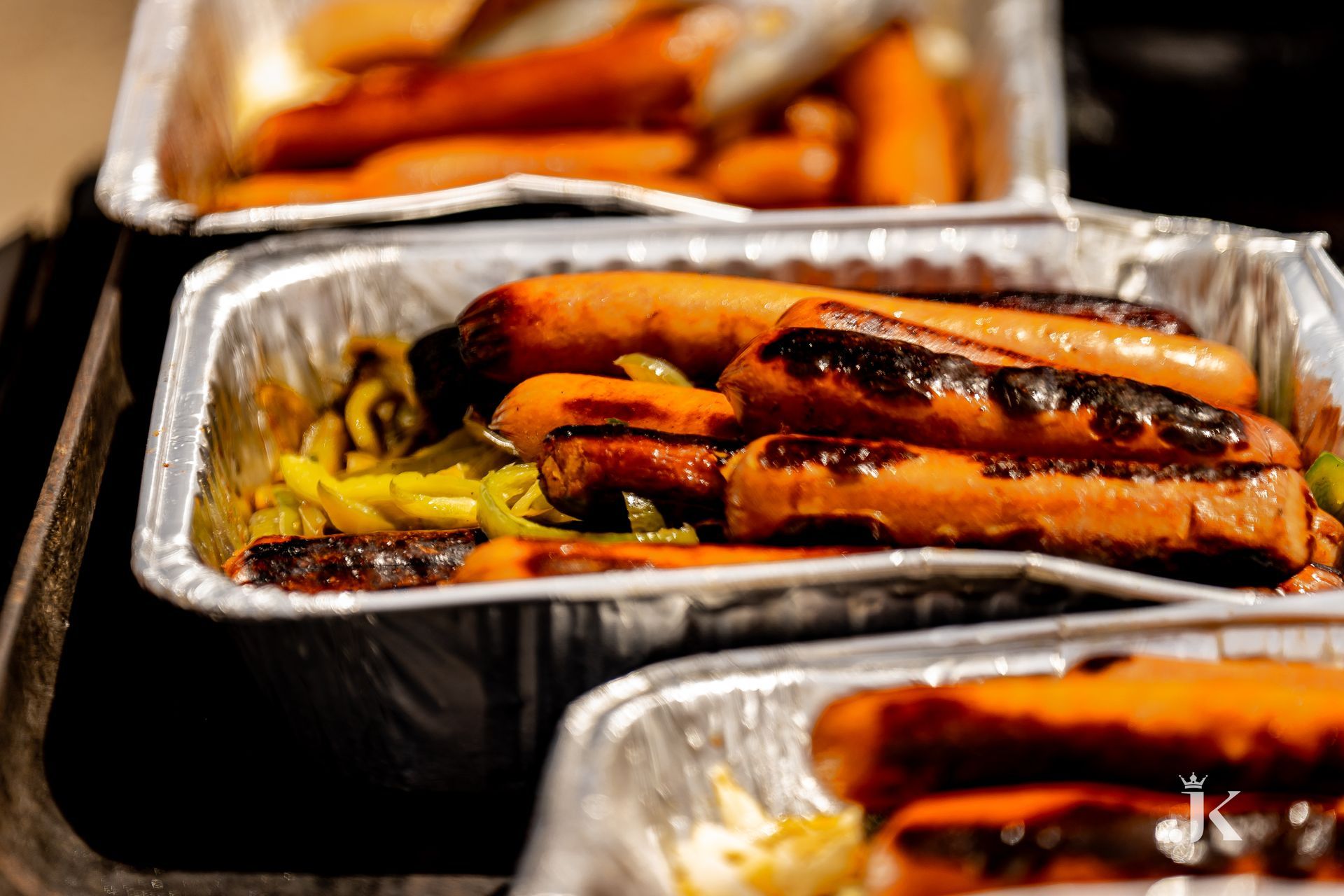 Aluminum foil containers filled with carrots and hot dogs on a table.