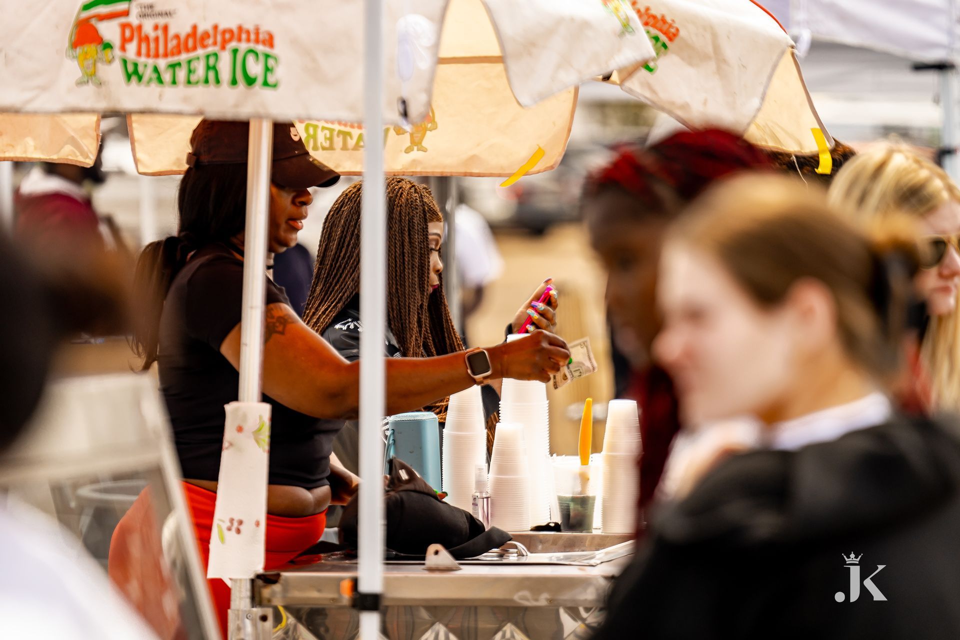 A woman is standing behind a philadelphia water ice stand