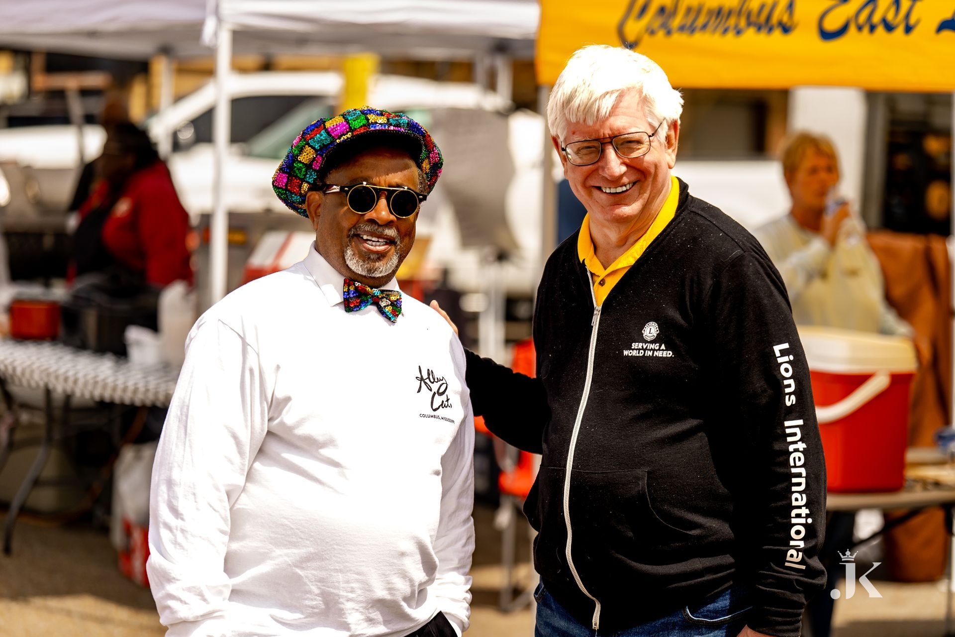 Two men are standing next to each other in front of a tent.