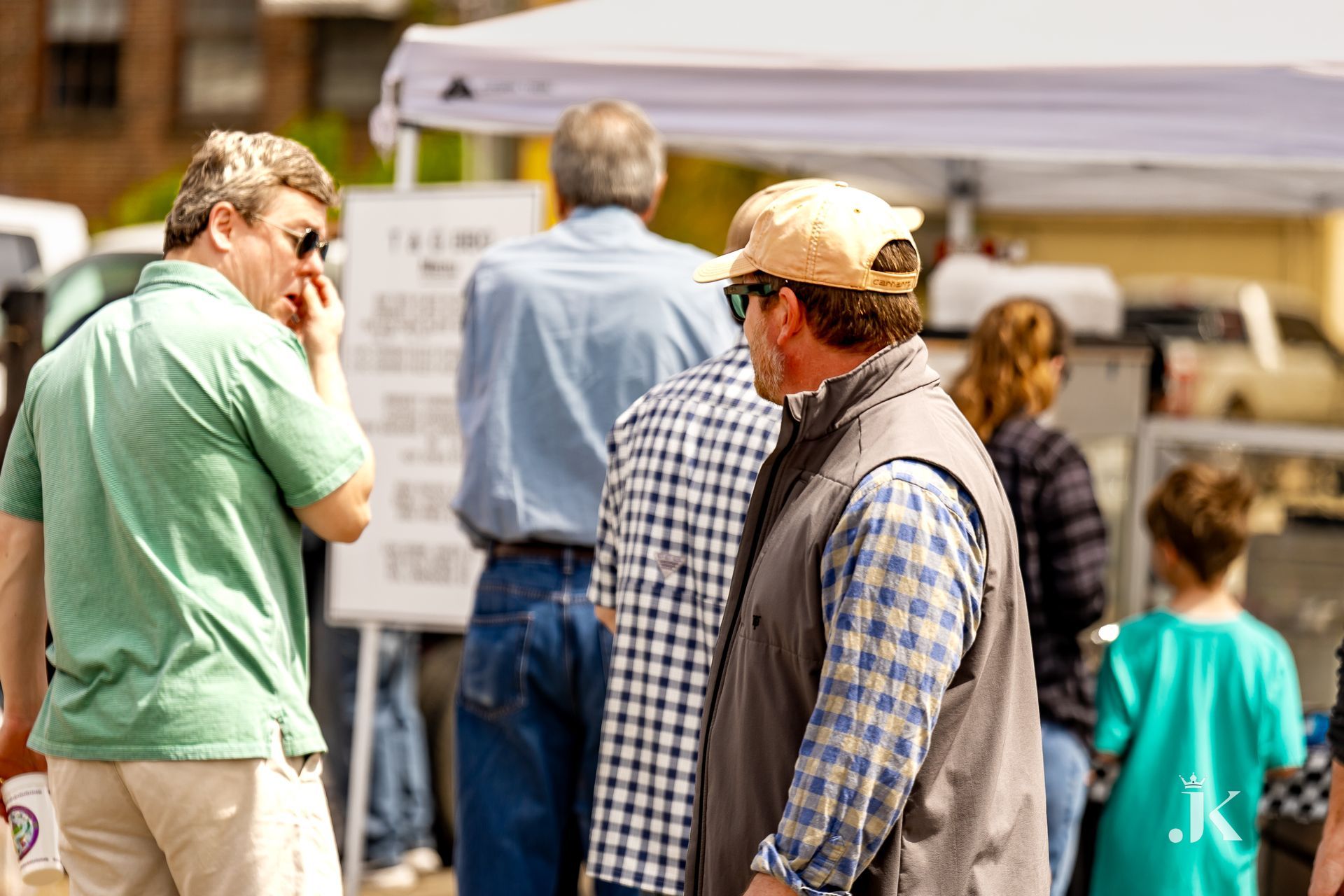 A group of people are standing under a tent talking to each other.