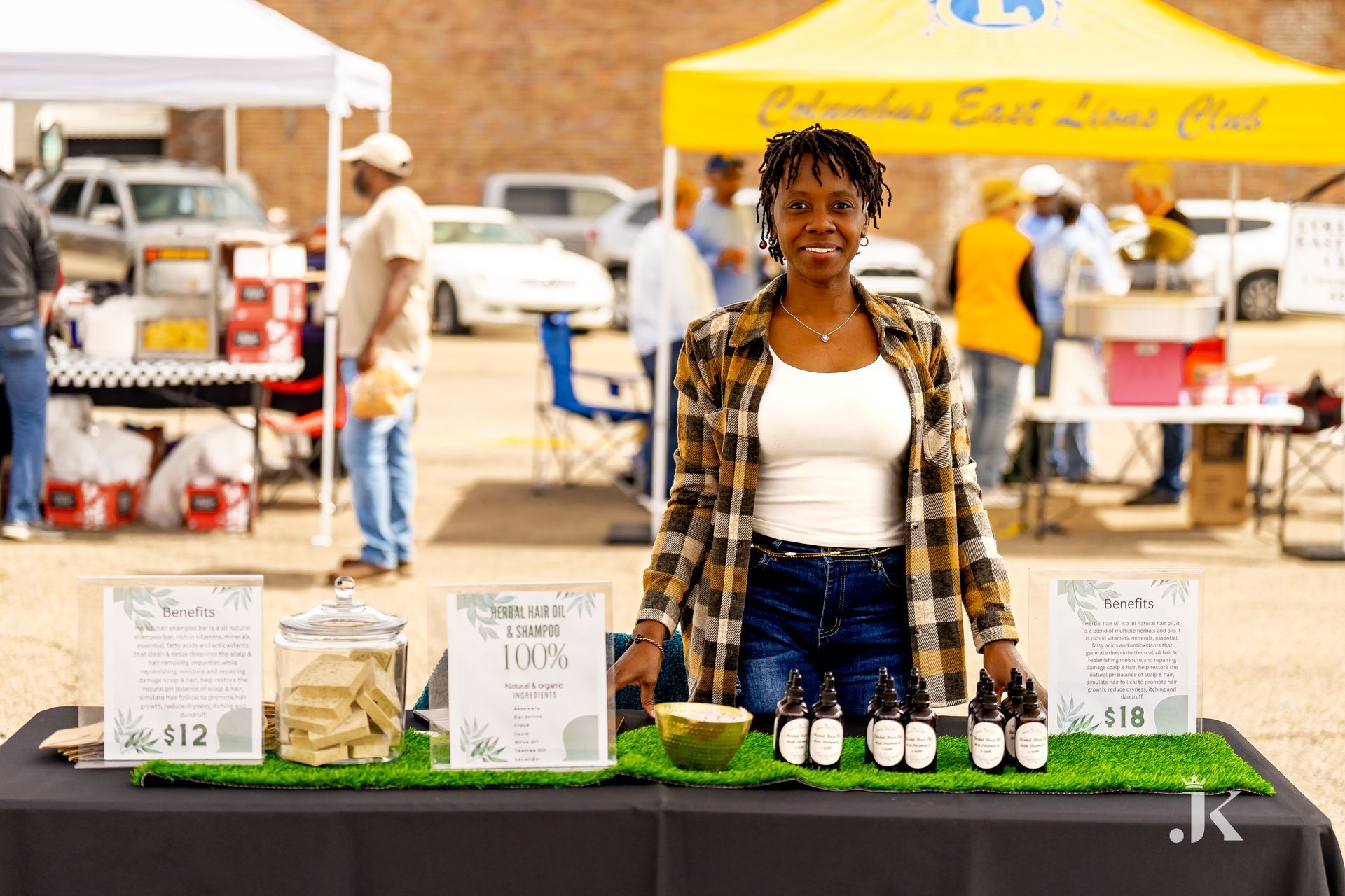A woman is standing in front of a table with bottles of beer on it.