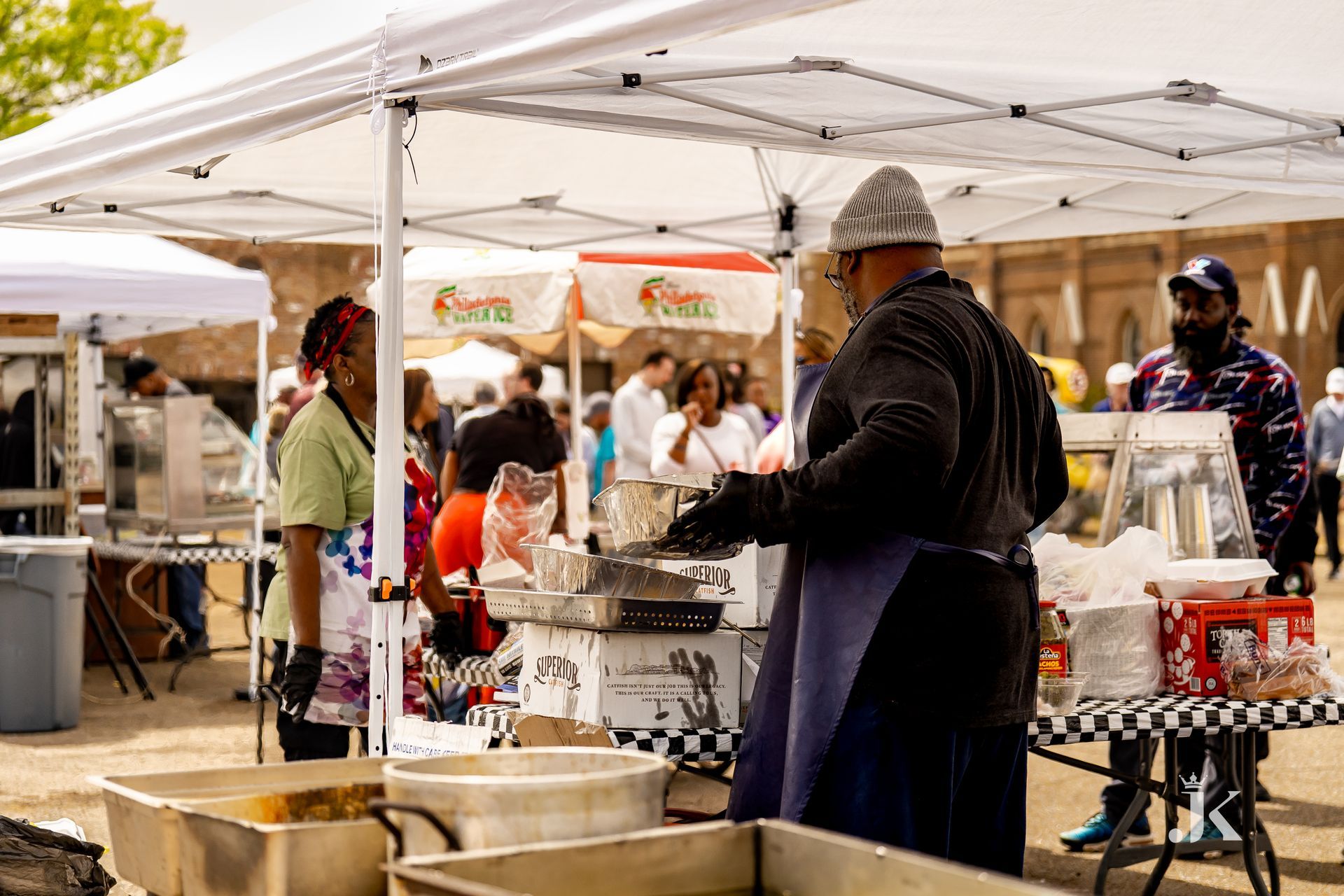 A man is cooking food under a tent at a market.