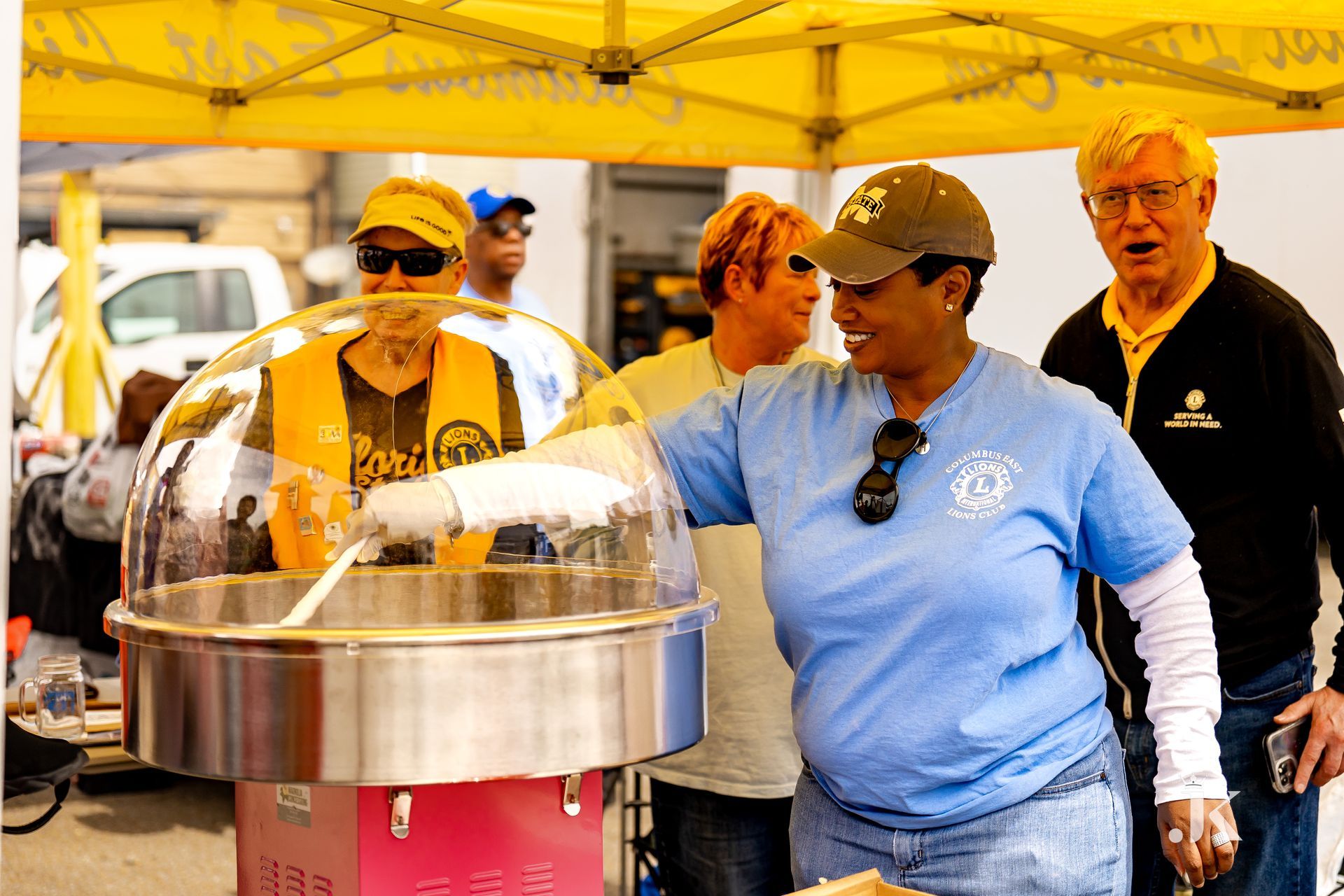A woman in a blue shirt is standing in front of a cotton candy machine