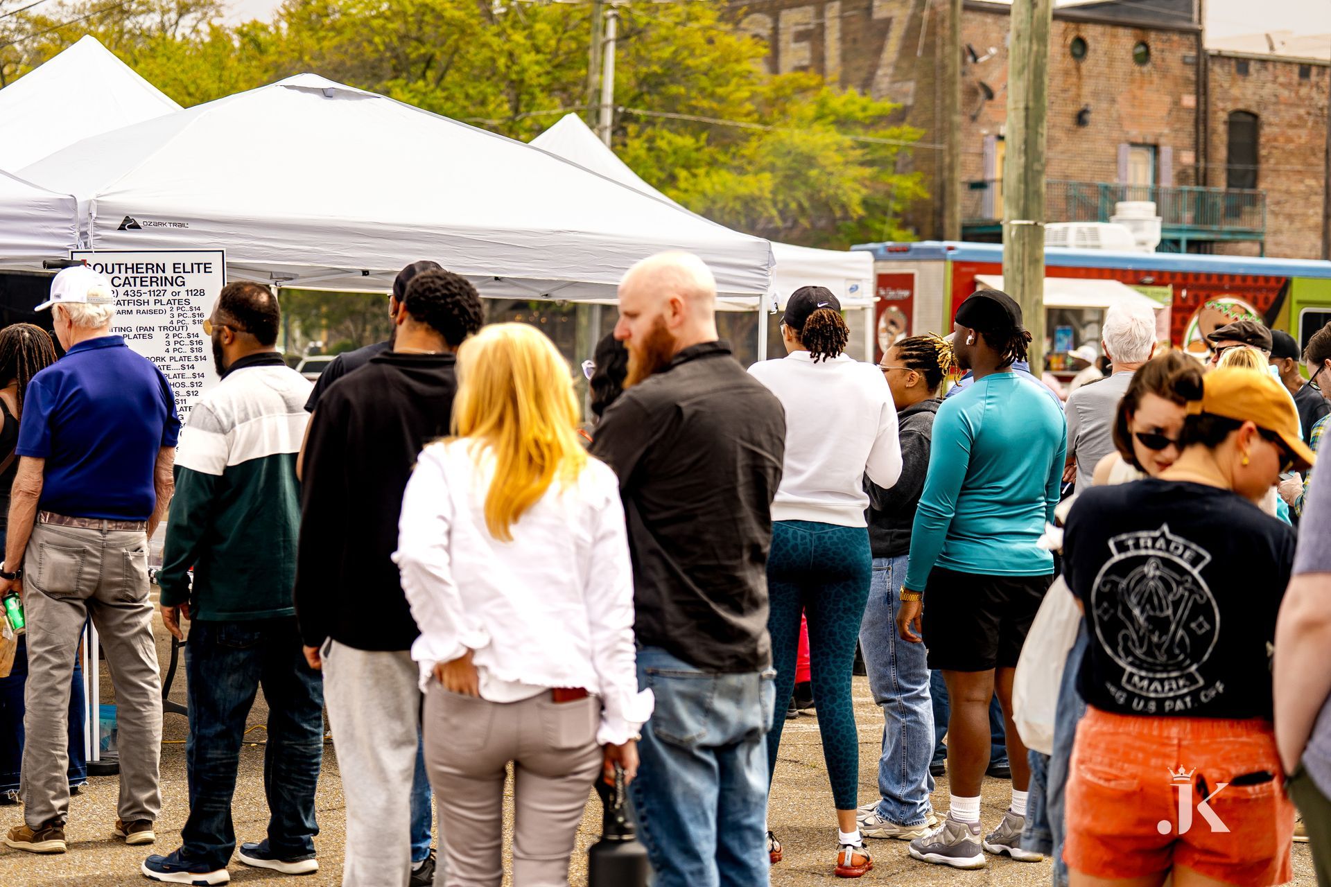 A group of people are standing in front of tents at a festival.