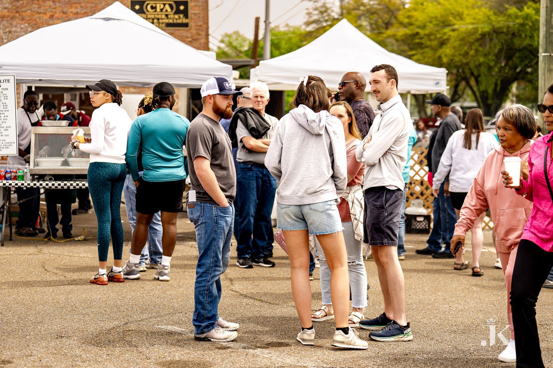 A group of people are standing in front of tents at a festival.