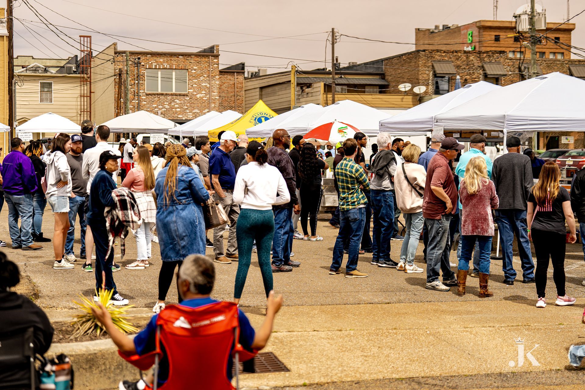 A man in a red chair is sitting in front of a crowd of people at a festival.