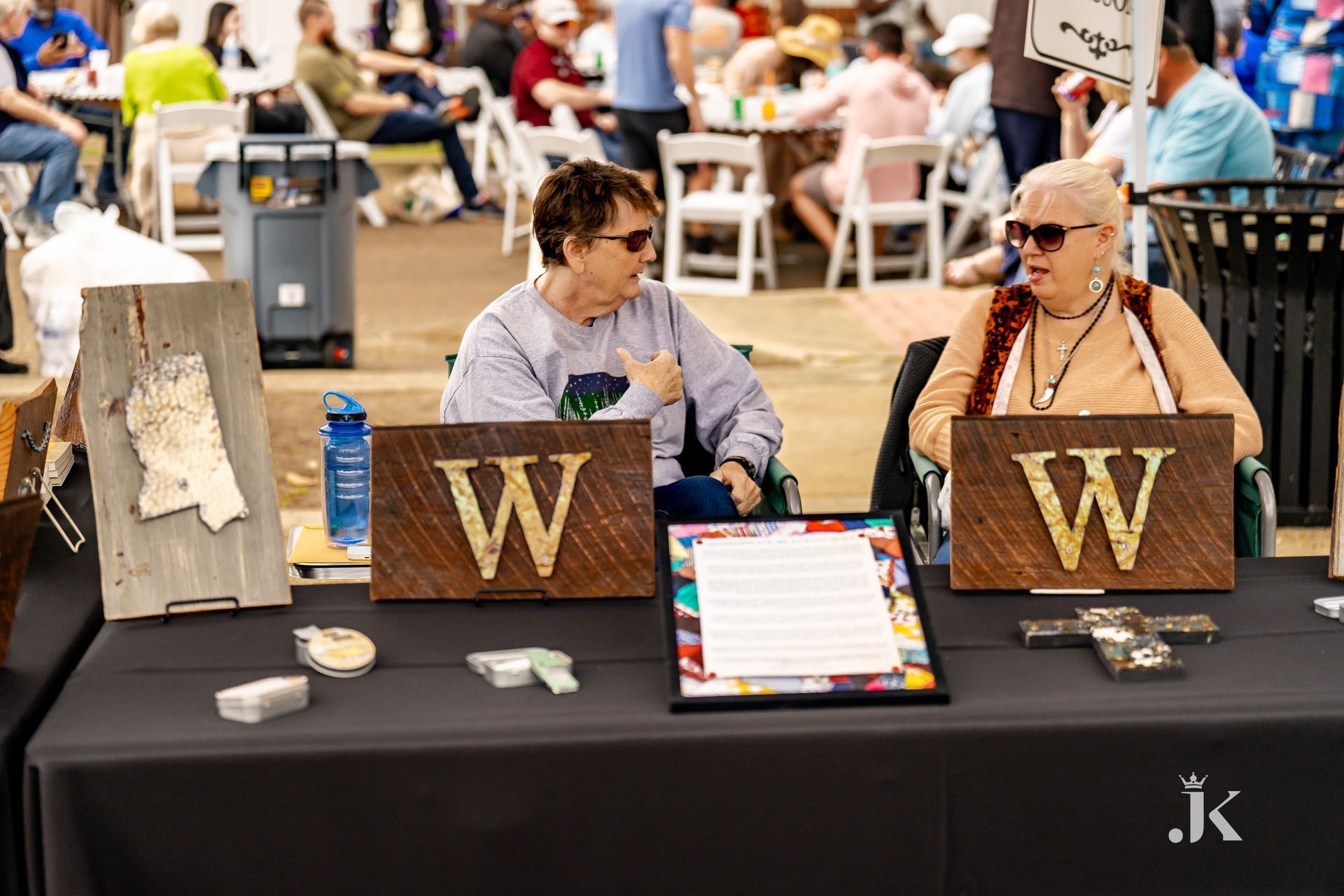 Two women are sitting at a table with wooden signs with the letter w on them.