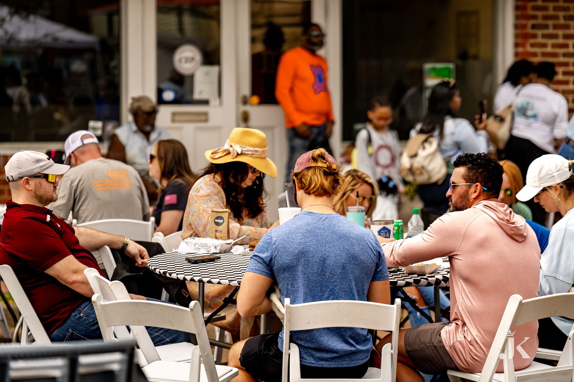 A group of people are sitting at tables outside of a restaurant.