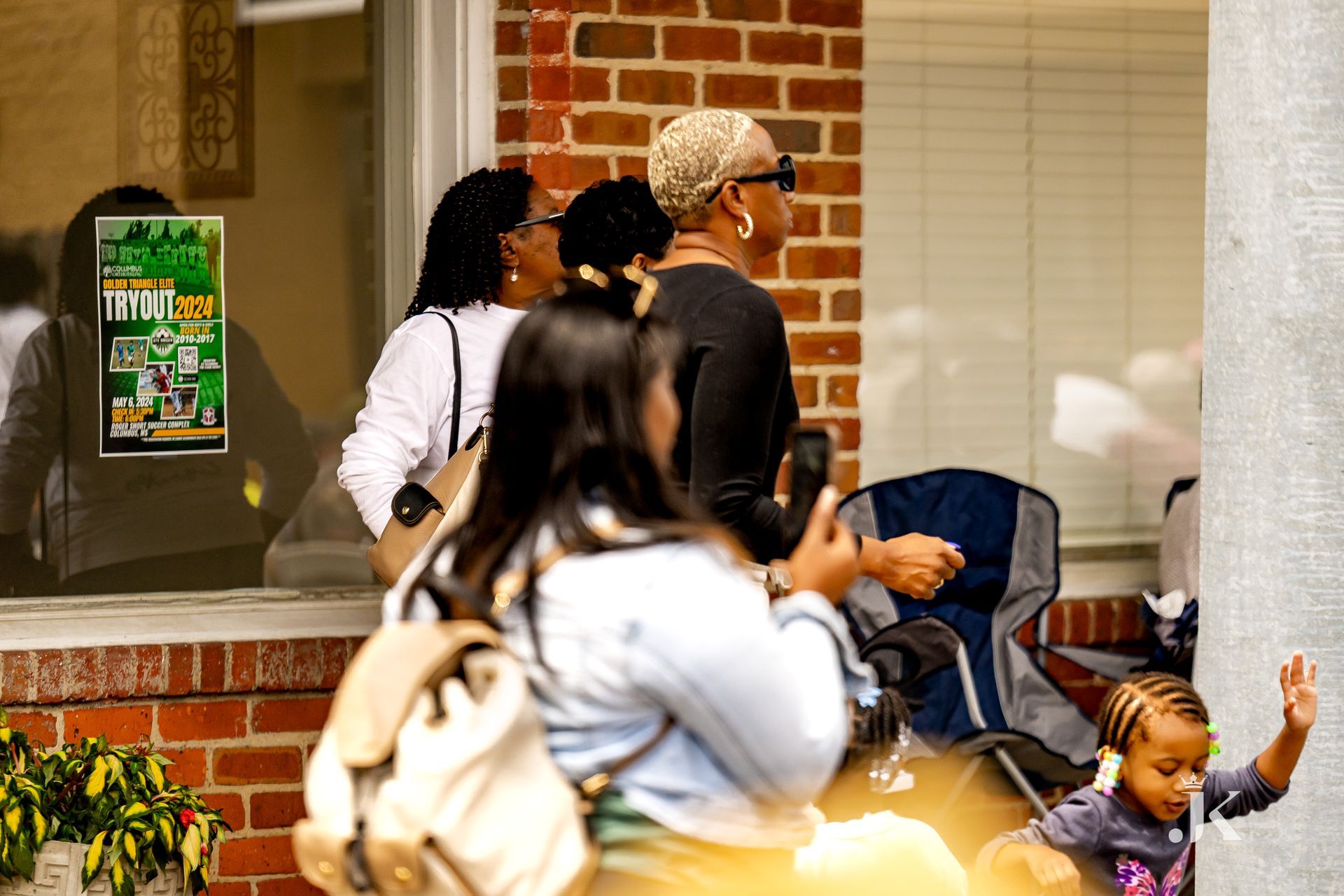 A group of people are standing in front of a brick building.