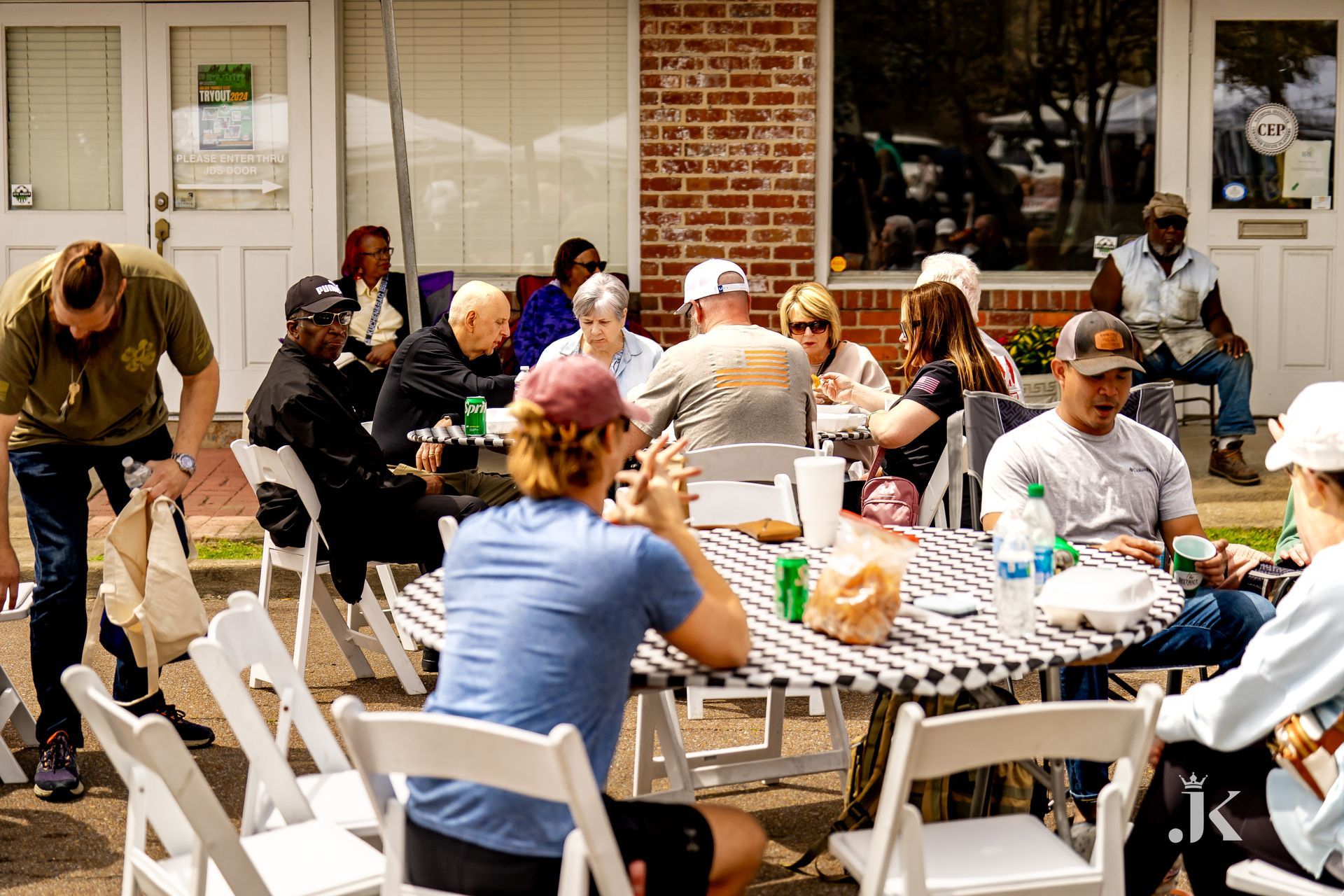 A group of people are sitting at a table outside of a building.