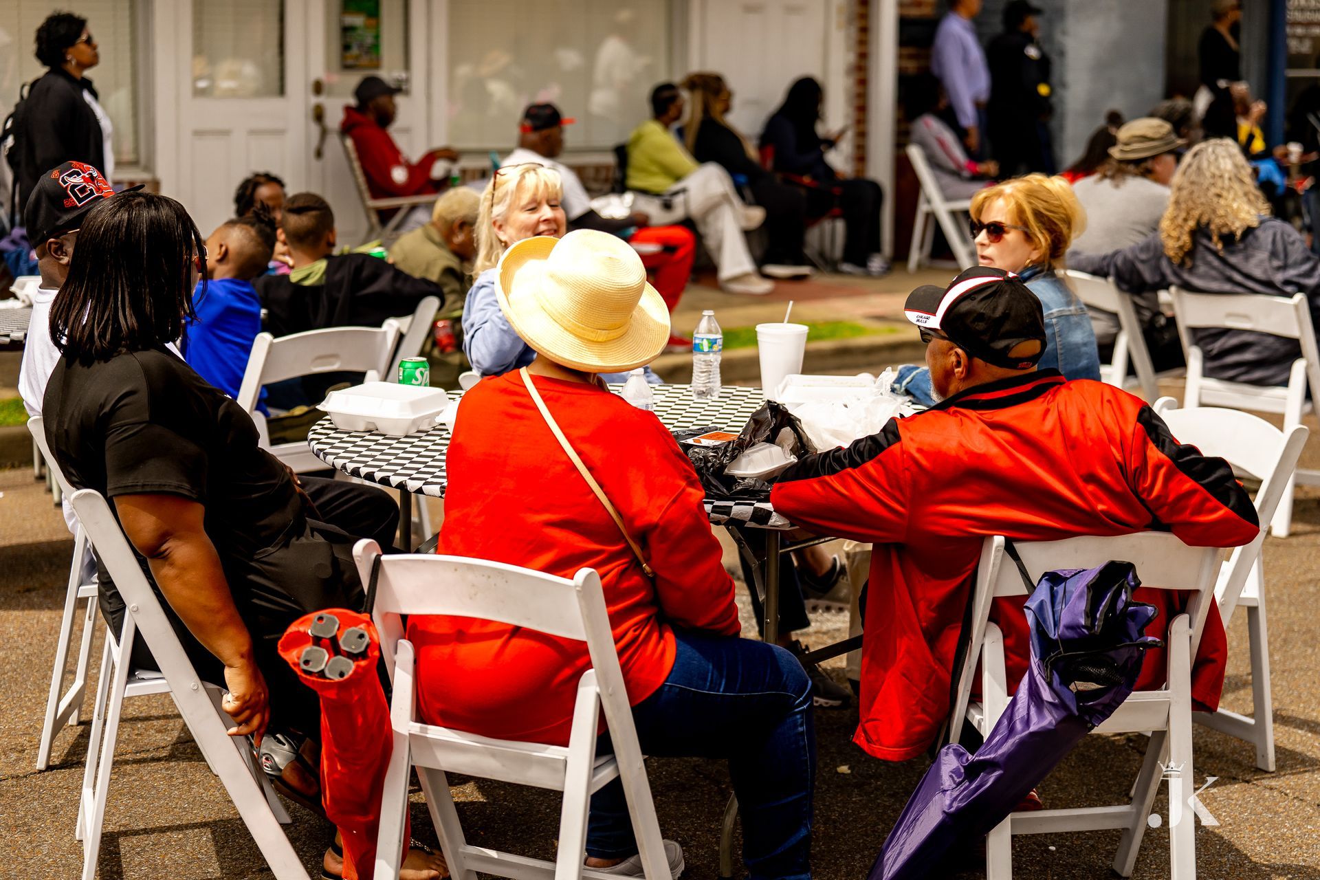 A group of people are sitting around a table in white folding chairs.