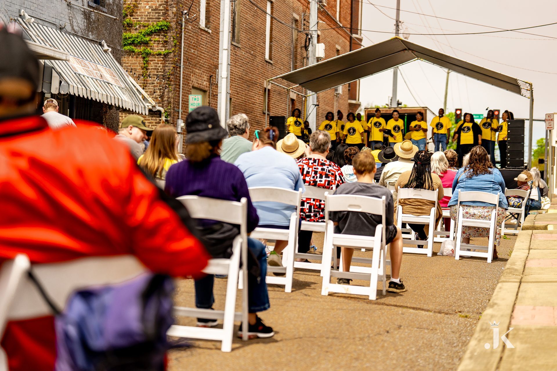 A group of people are sitting in white chairs in front of a stage.