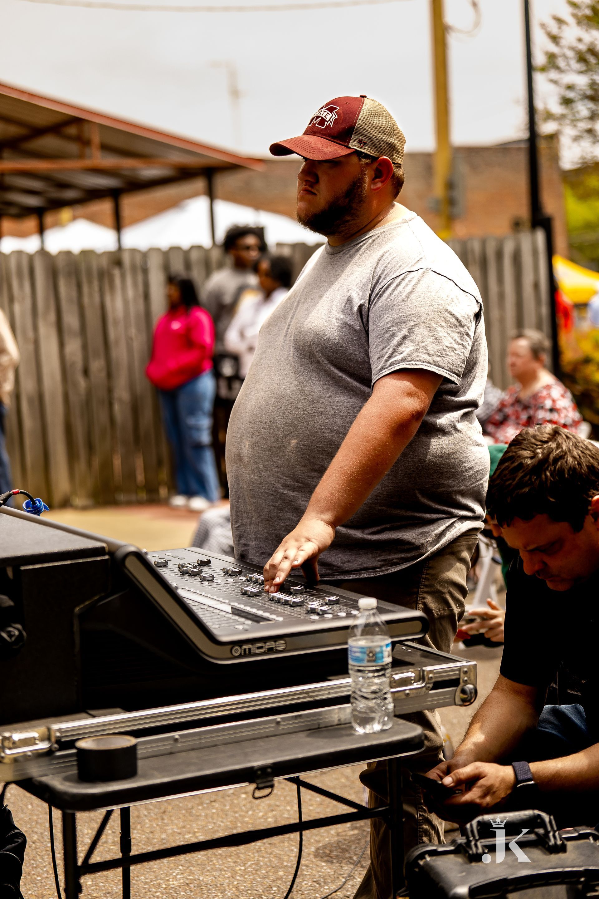 A man is standing in front of a mixer while another man works on it.