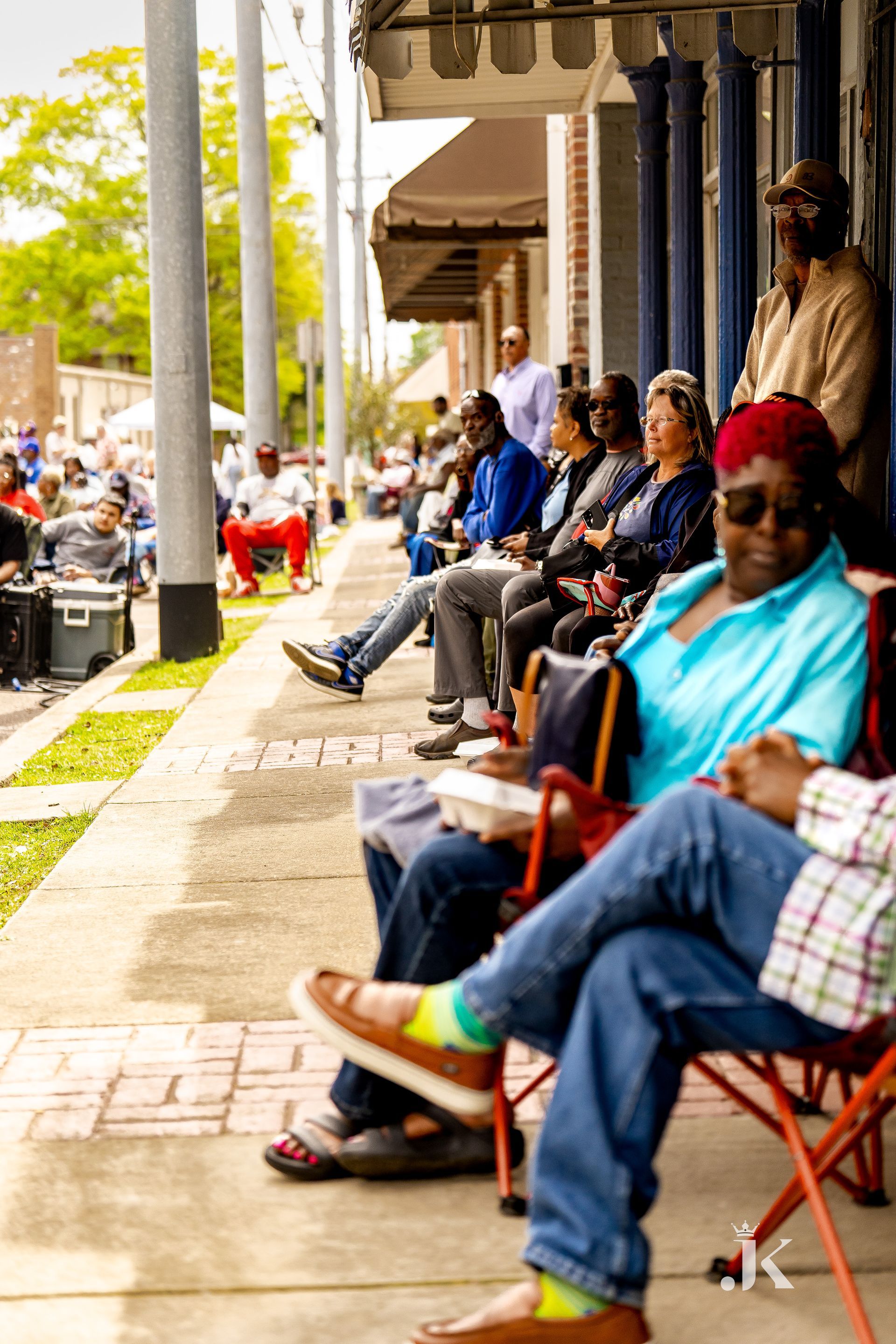 A group of people are sitting on a sidewalk in front of a building