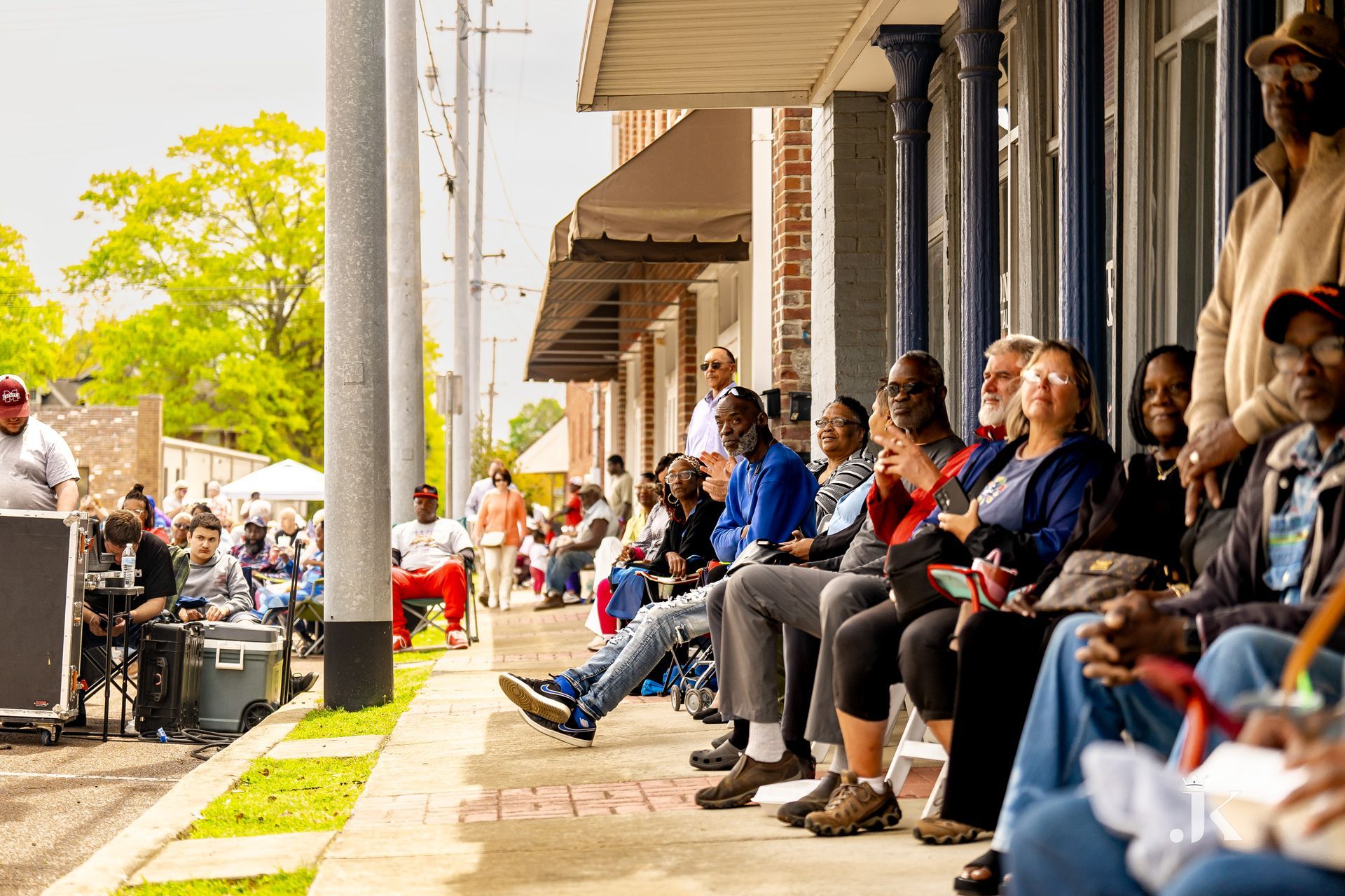 A group of people are sitting on a porch watching a parade.