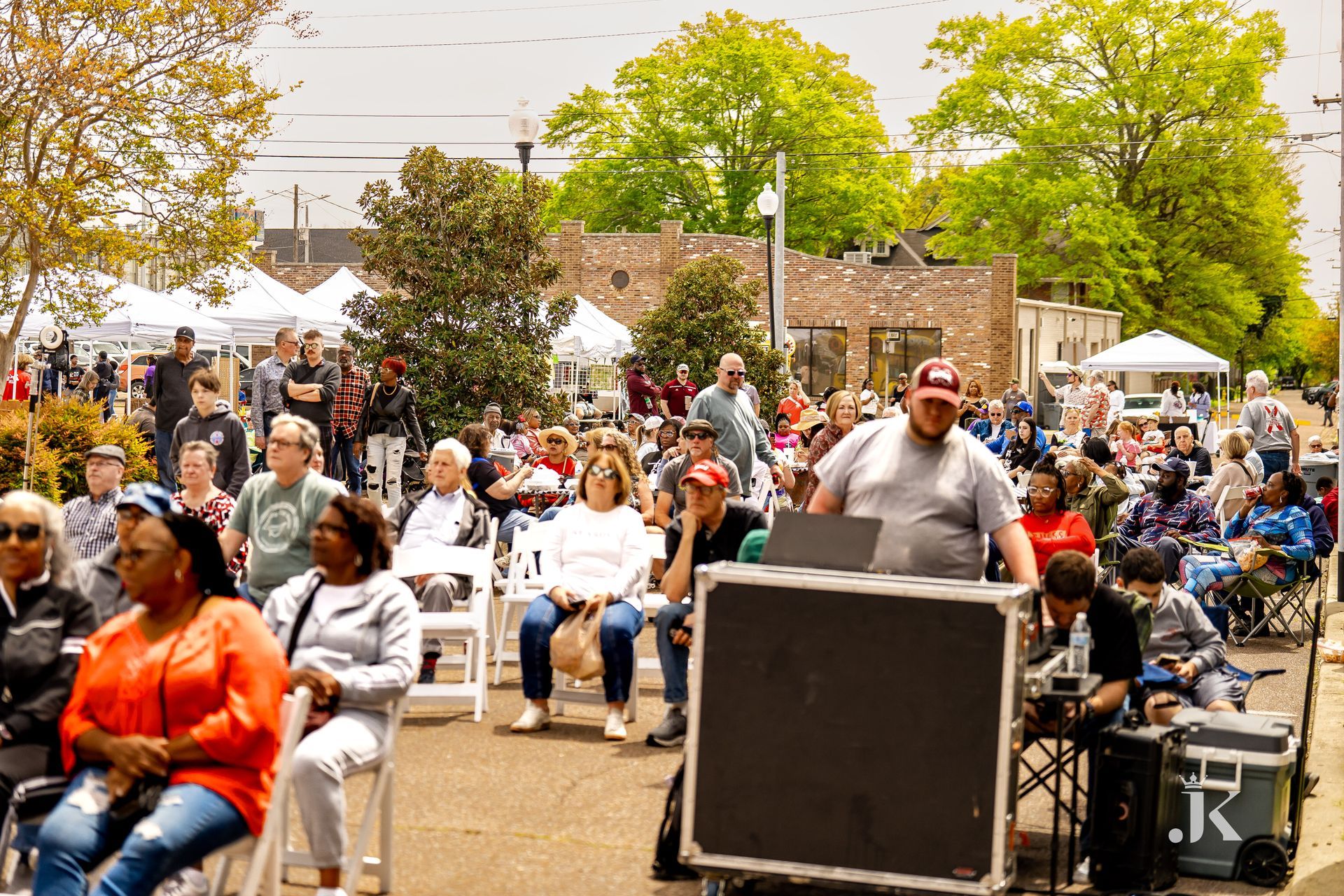 A large group of people are sitting in chairs in a park.